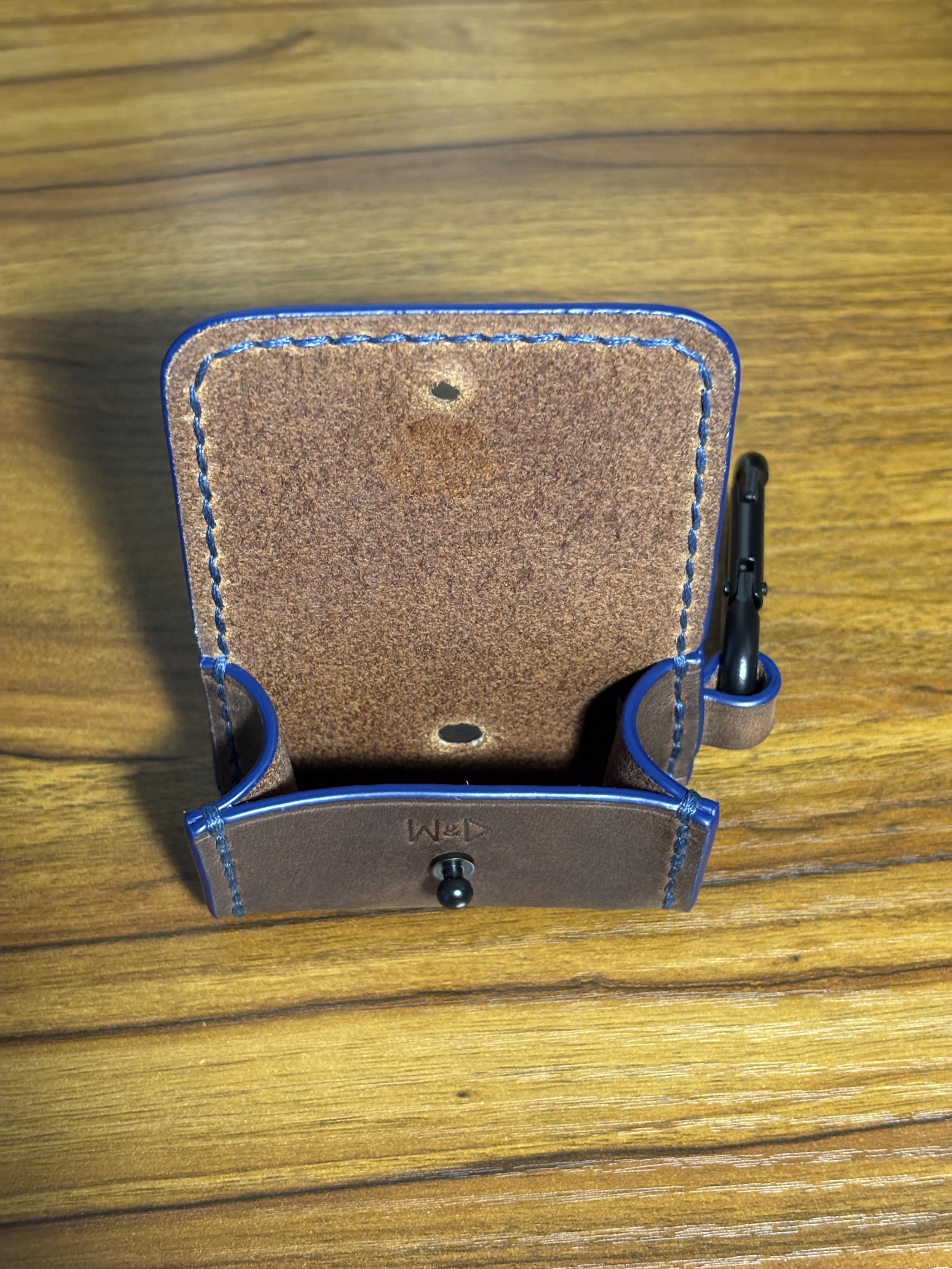 Open leather dog waste bag dispenser showing interior and stud closure.