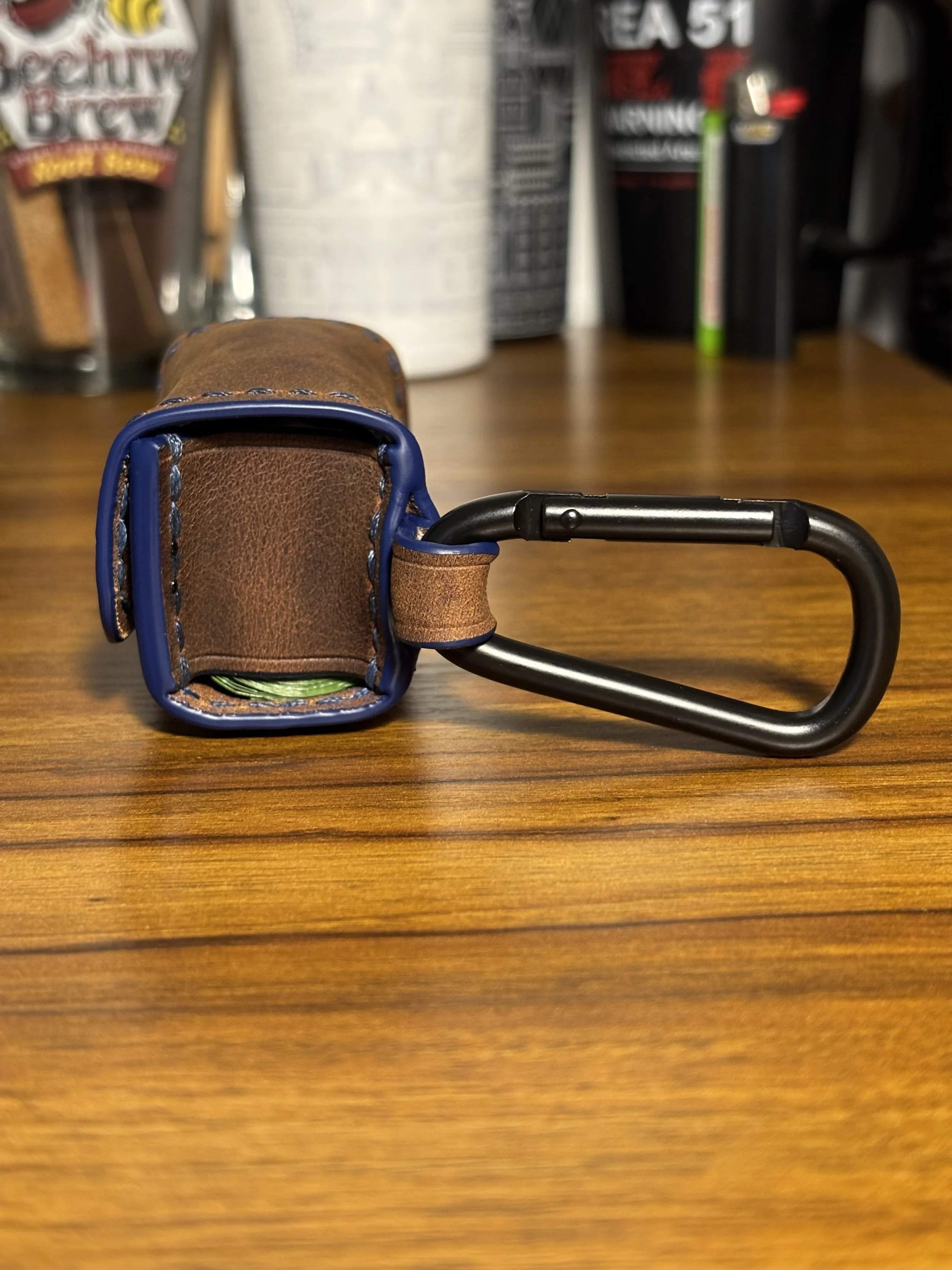 Opposite side profile of leather dog waste bag holder with attached carabiner.