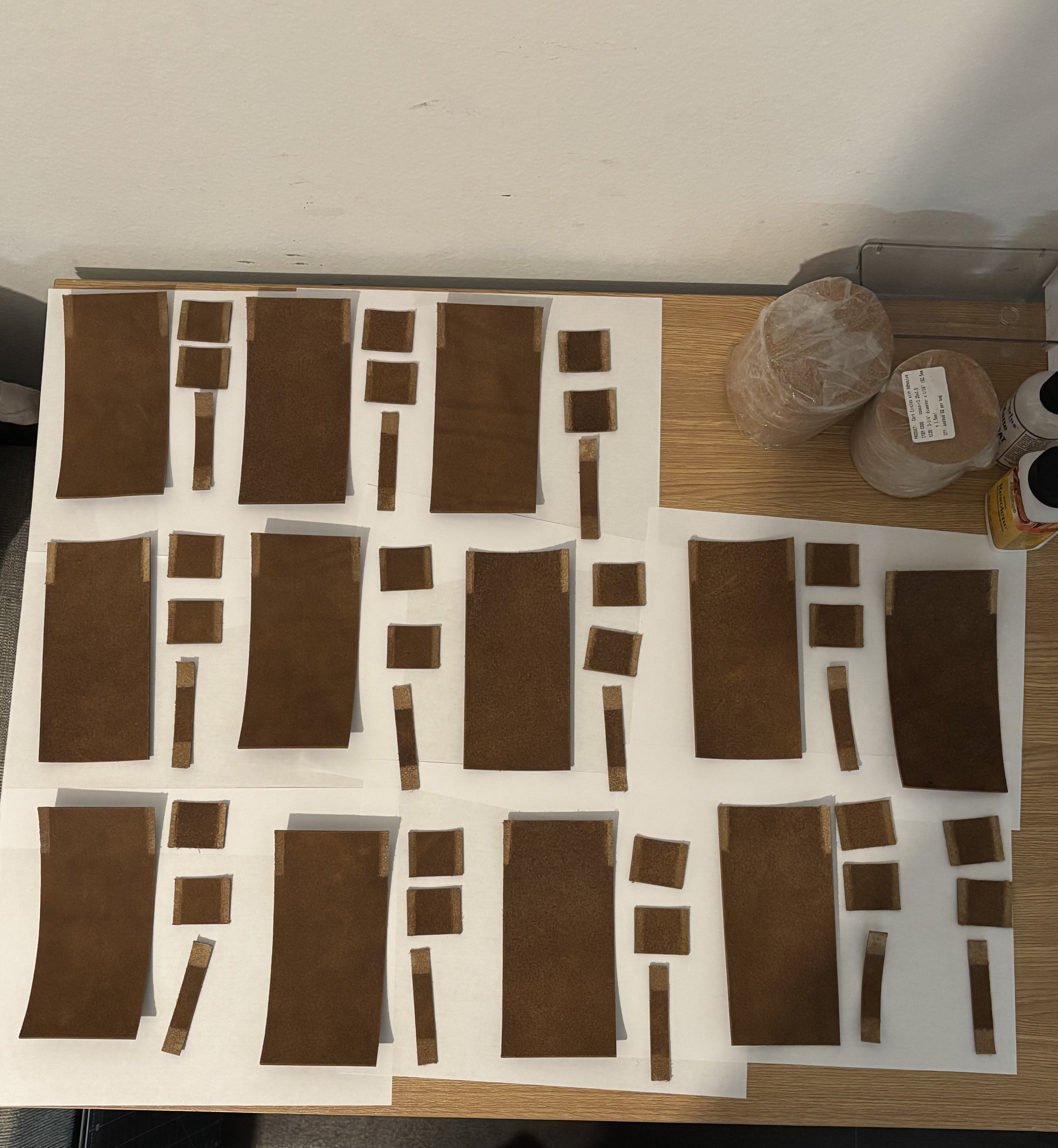 Overhead view of precision-cut Seidel Crazy Horse leather components laid out on a workshop table featuring 96 hand-skived edges for dog waste bag holders.