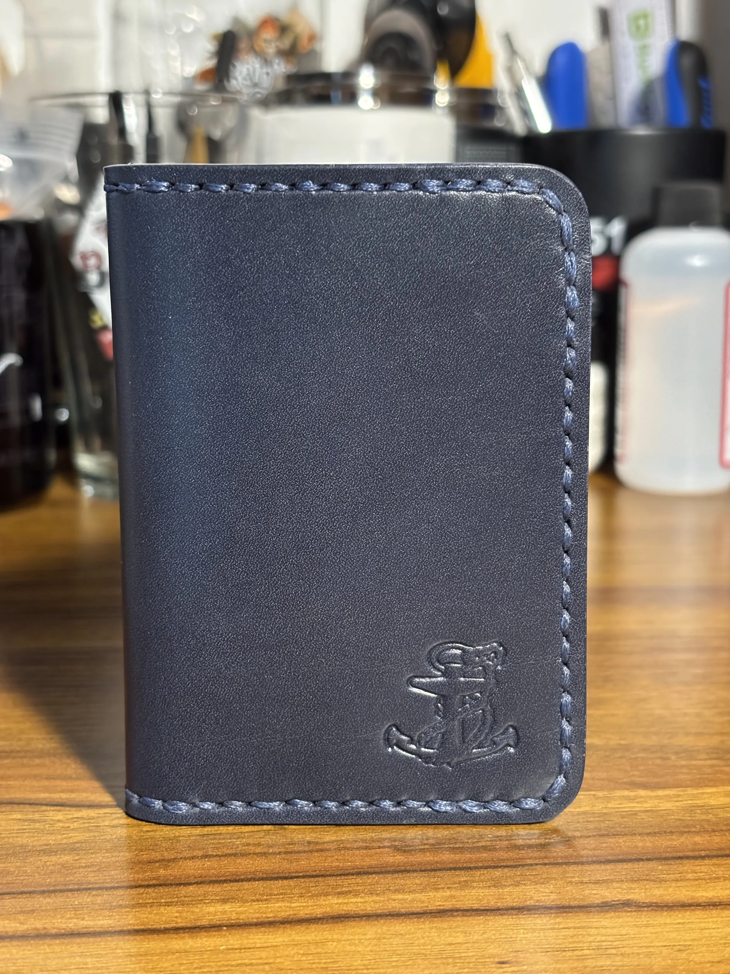 The Kraken handmade navy blue leather bifold wallet with debossed anchor and hand saddle stitching.