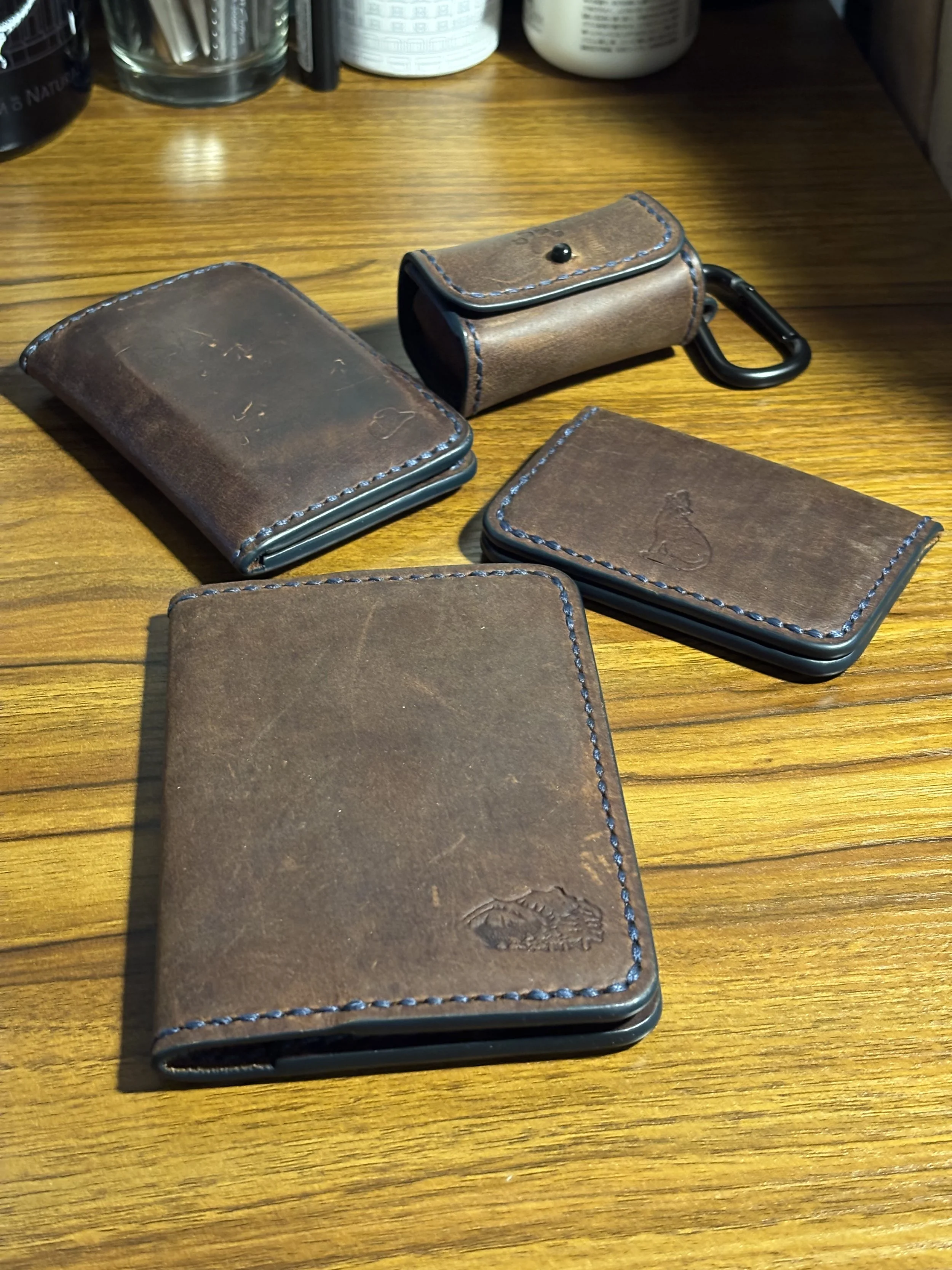 Handcrafted pull-up brown leather goods collection by The Wolf and The Dog Leather Co., featuring bifold wallets, card case, passport case, and dog waste bag dispenser.