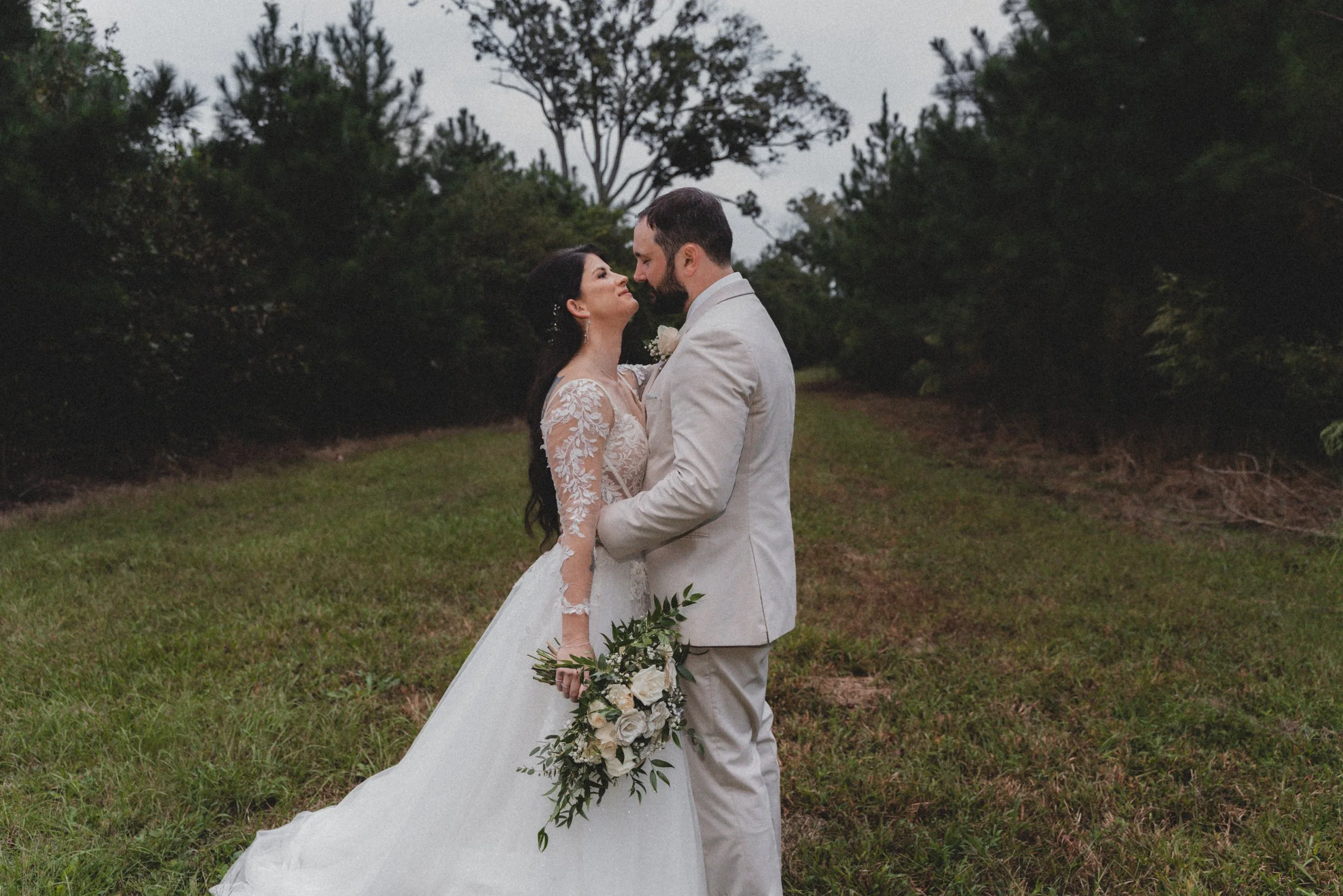 bride and groom facing each other in front of a wooded background