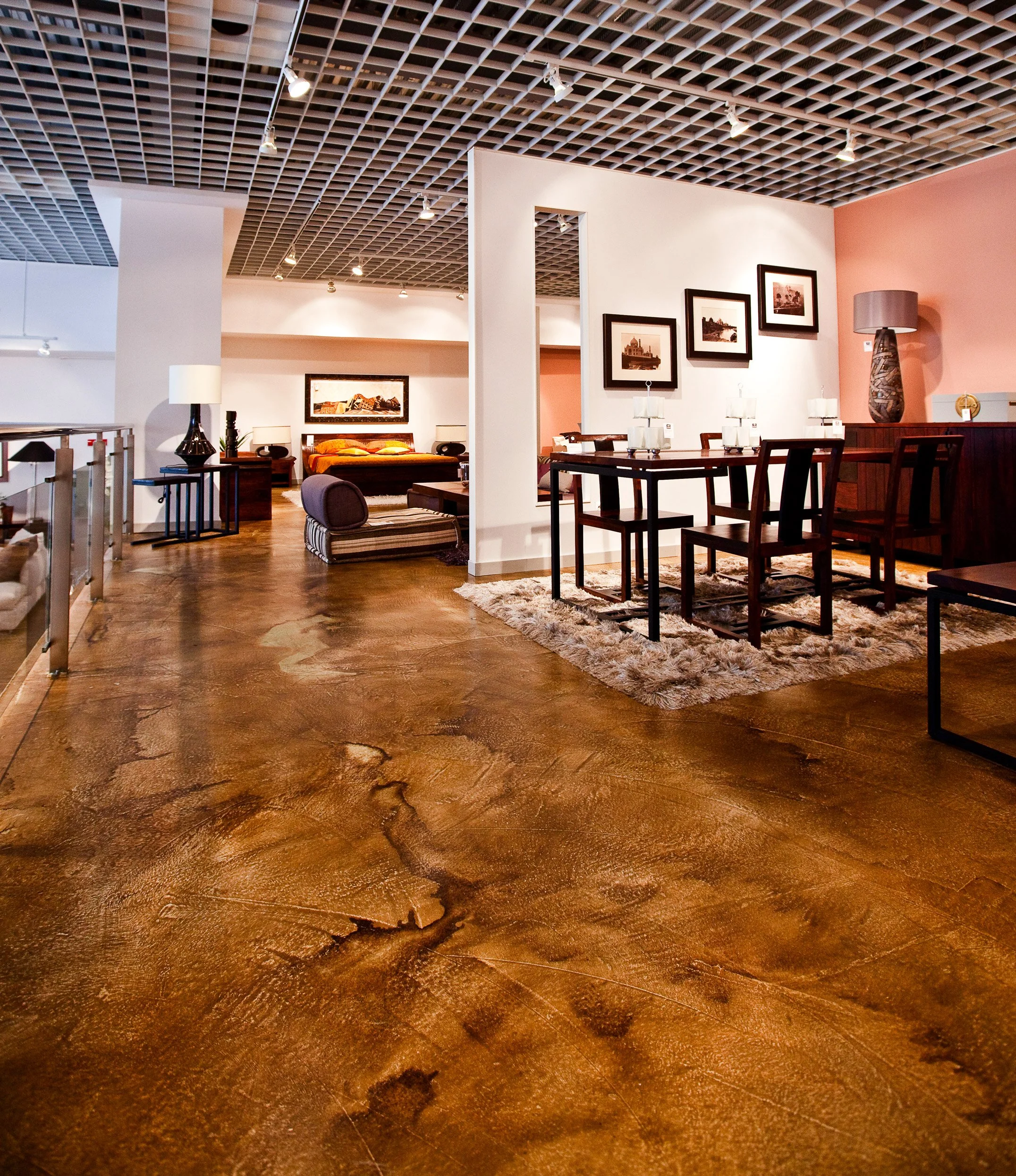 Intérieur d'une salle à manger avec un tapis shaggy, une table en bois avec six chaises, et une chambre avec un lit en arrière-plan, décorée avec des lampes et des tableaux.