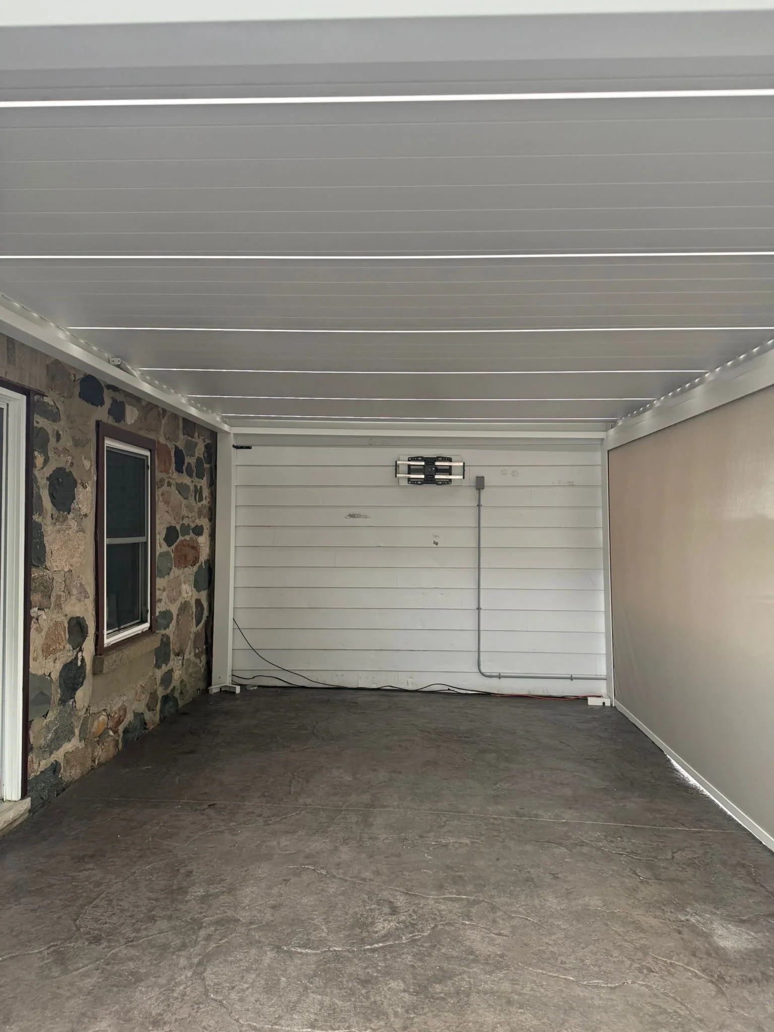 Empty garage with stone and siding walls, concrete floor, and a roller garage door.
