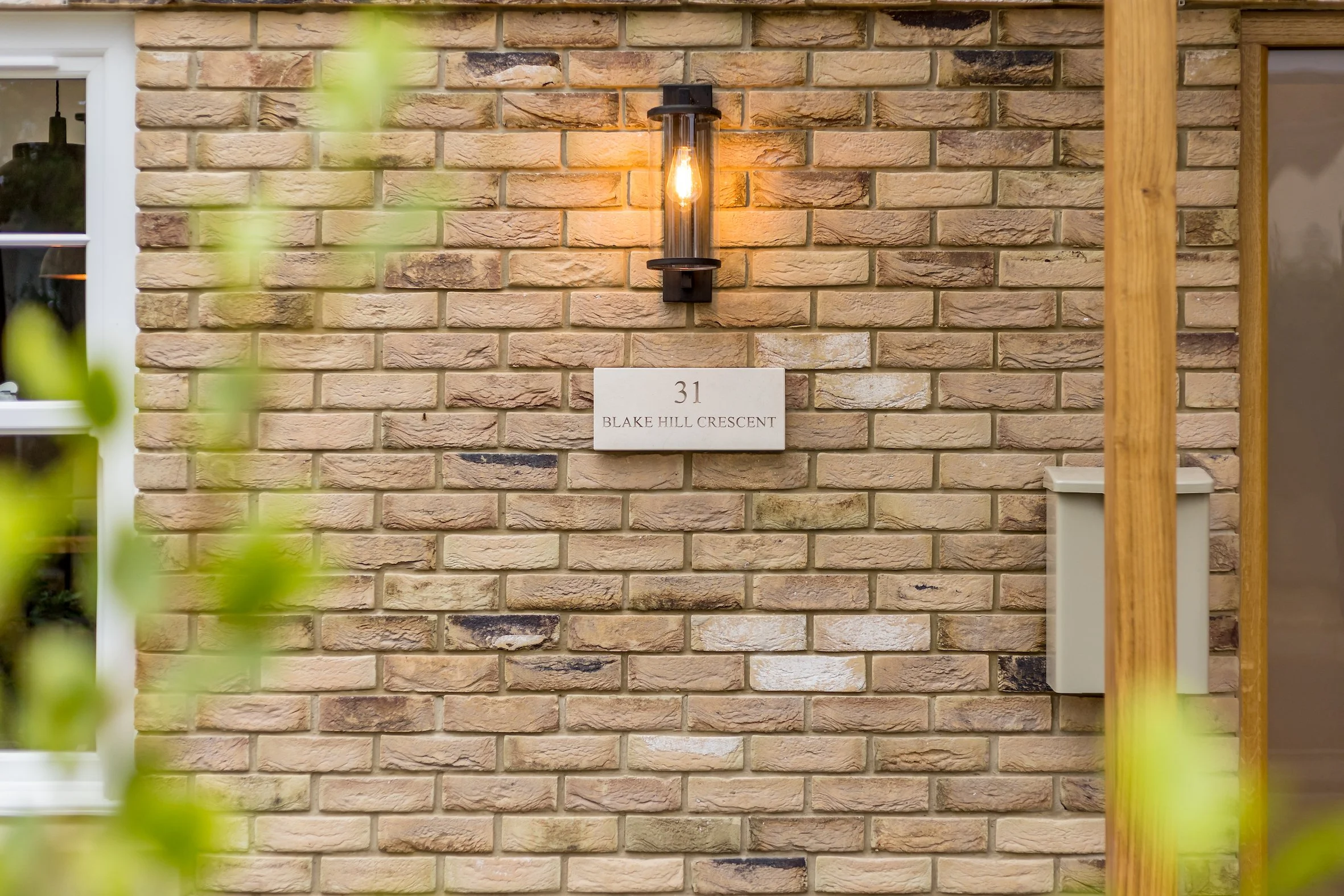 Brick wall with house number 31 and address Blake Hill Crescent, illuminated by a wall-mounted light fixture.