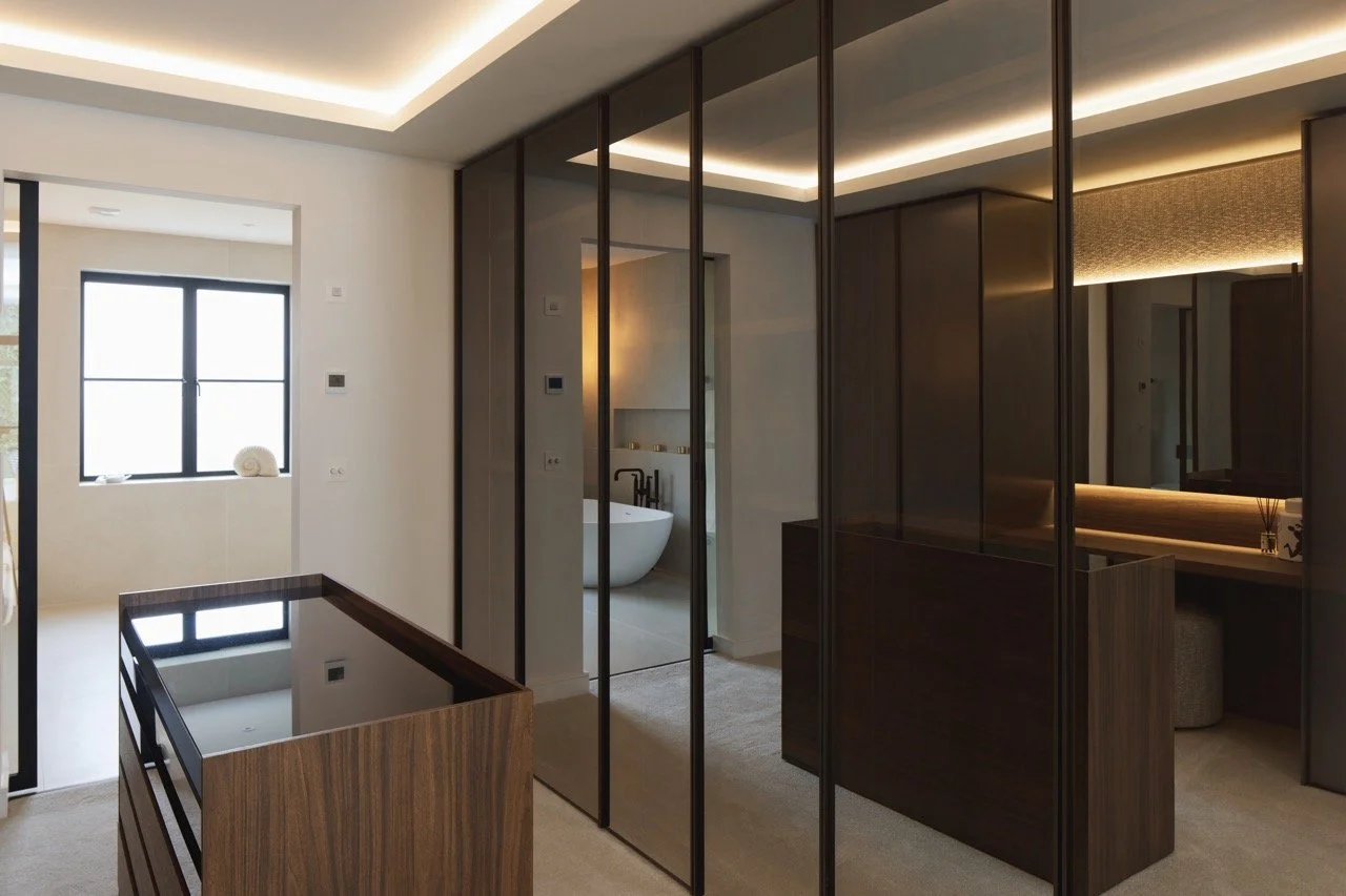 Modern interior bedroom with glass sliding doors, a window ledge with decorative items, and a bathroom with a freestanding bathtub visible through the door.