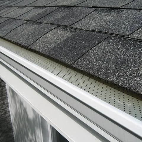 Close-up of asphalt shingles on a roof with a gutter system installed.