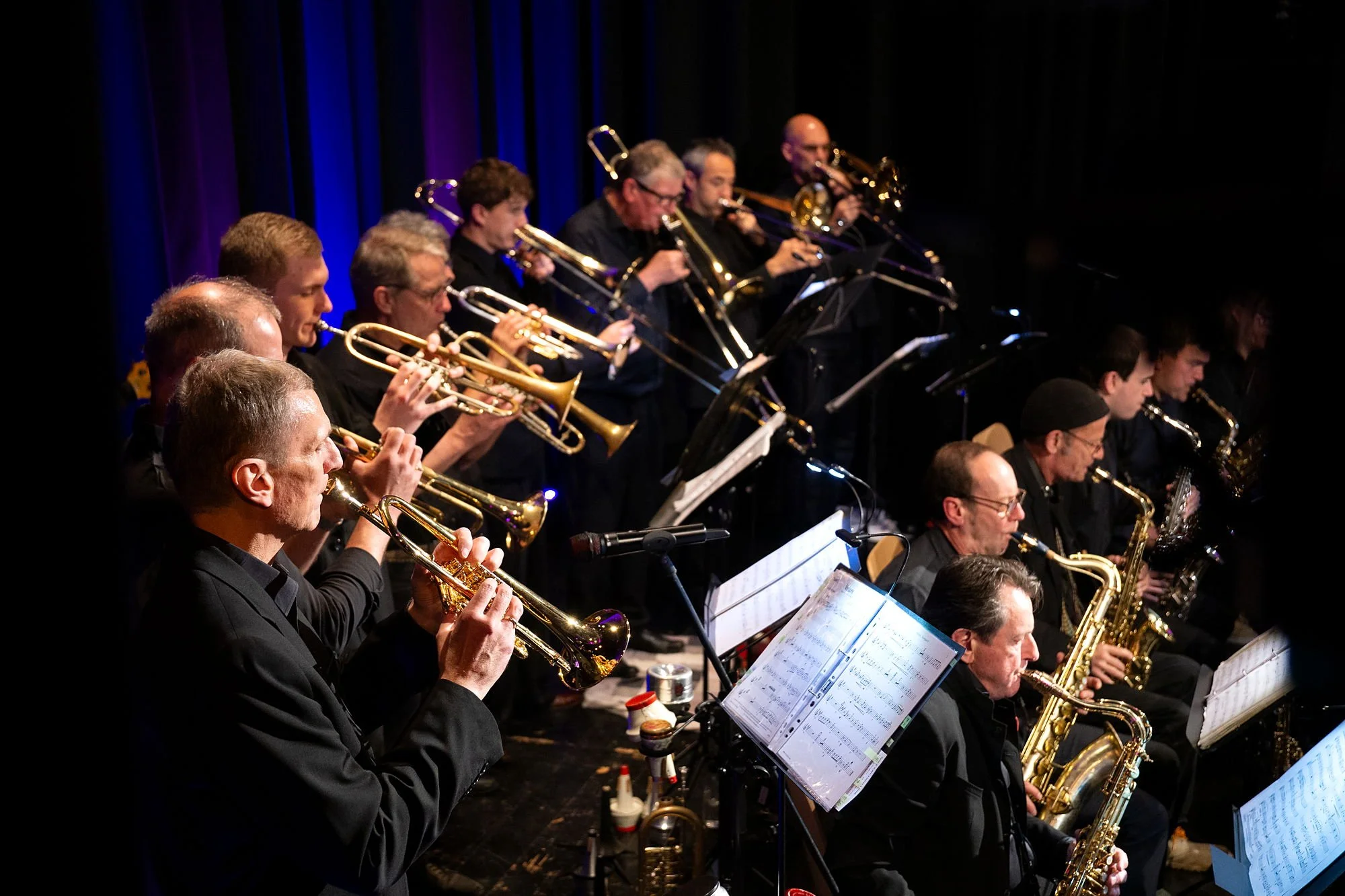 Trompeten und Saxophone der Bigband Vaterstetten im blauen Bühnenlicht