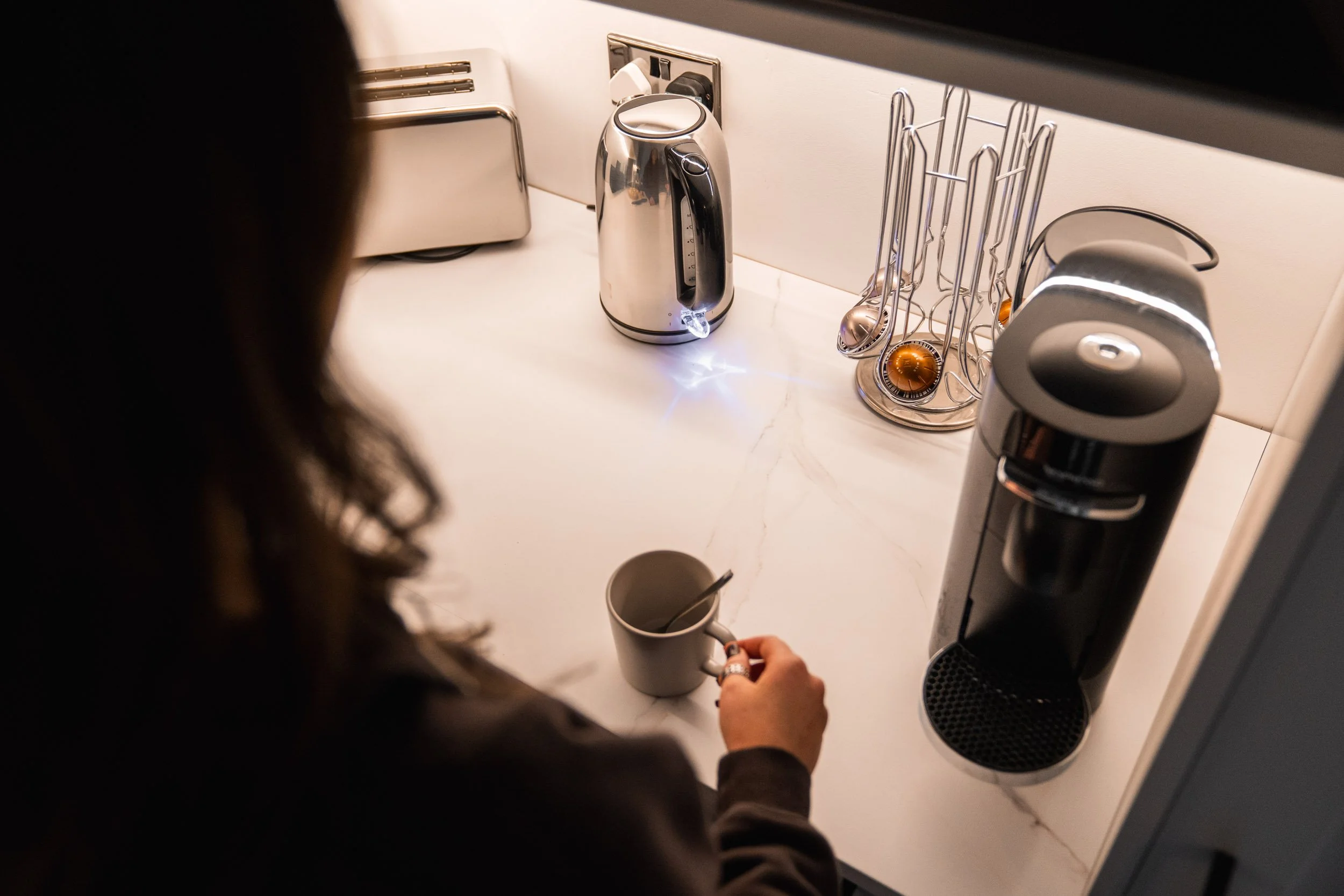 Person preparing a hot beverage with a coffee machine in a kitchen.