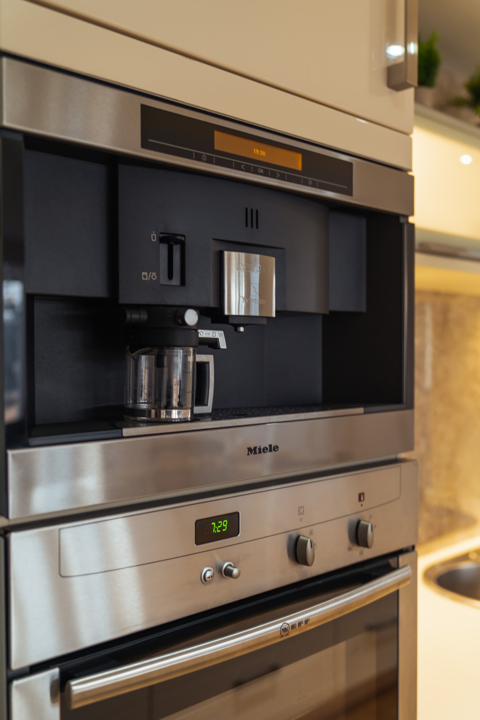 A stainless steel microwave with a coffee machine built into its front panel.