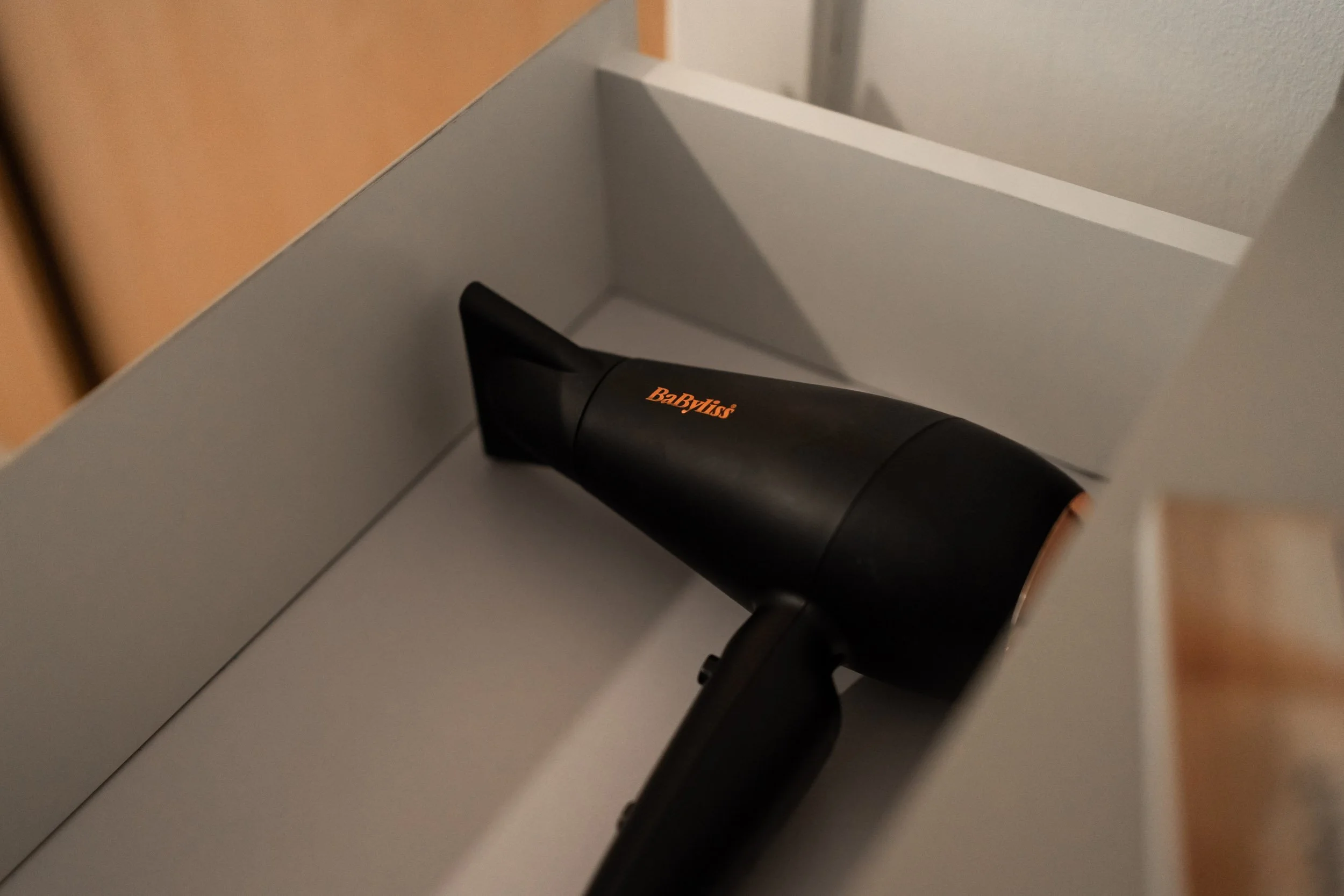 Black hair dryer with orange logo inside a gray box.