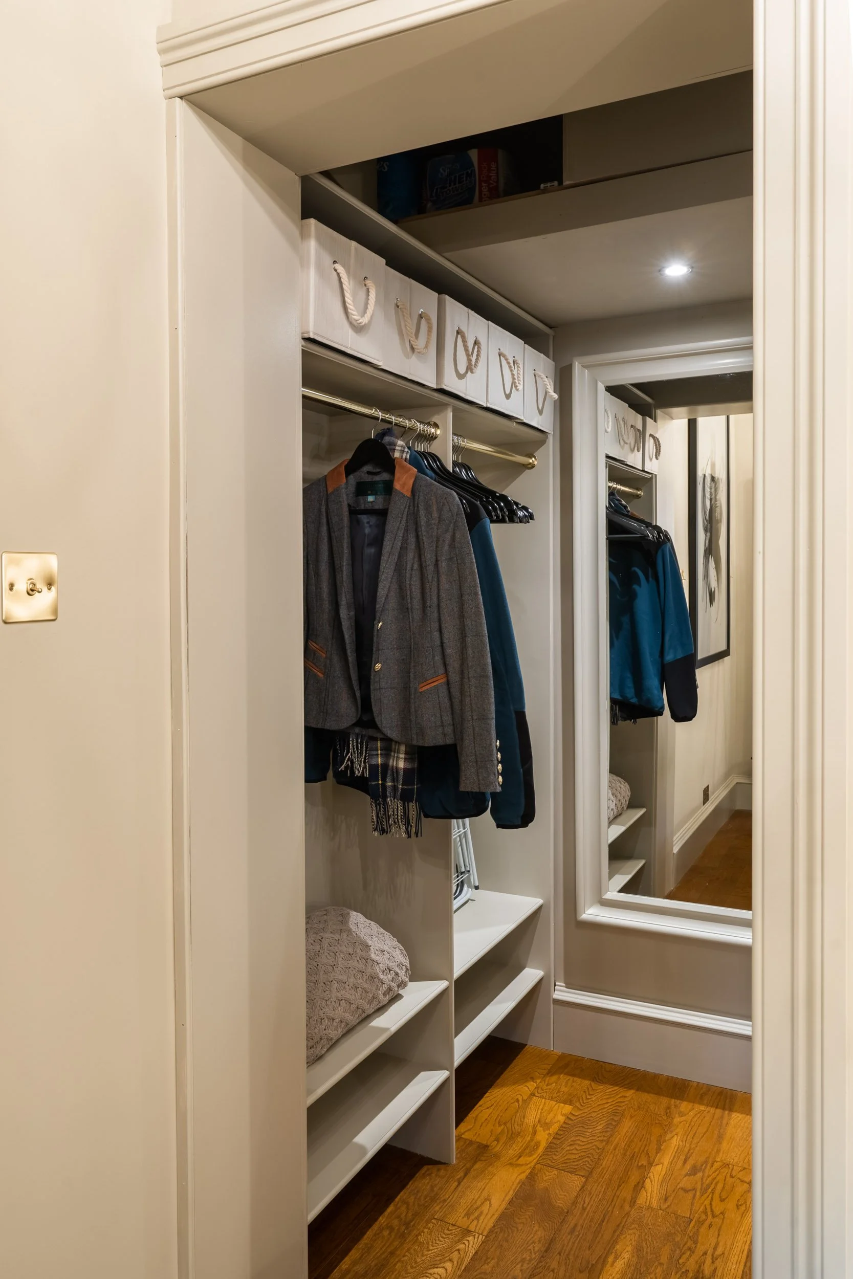 Closet with hanging clothes, shelves, storage boxes, and a full-length mirror.