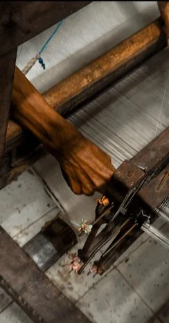overhead close-up of a hand guiding fibre through a traditional wooden spinning tool.