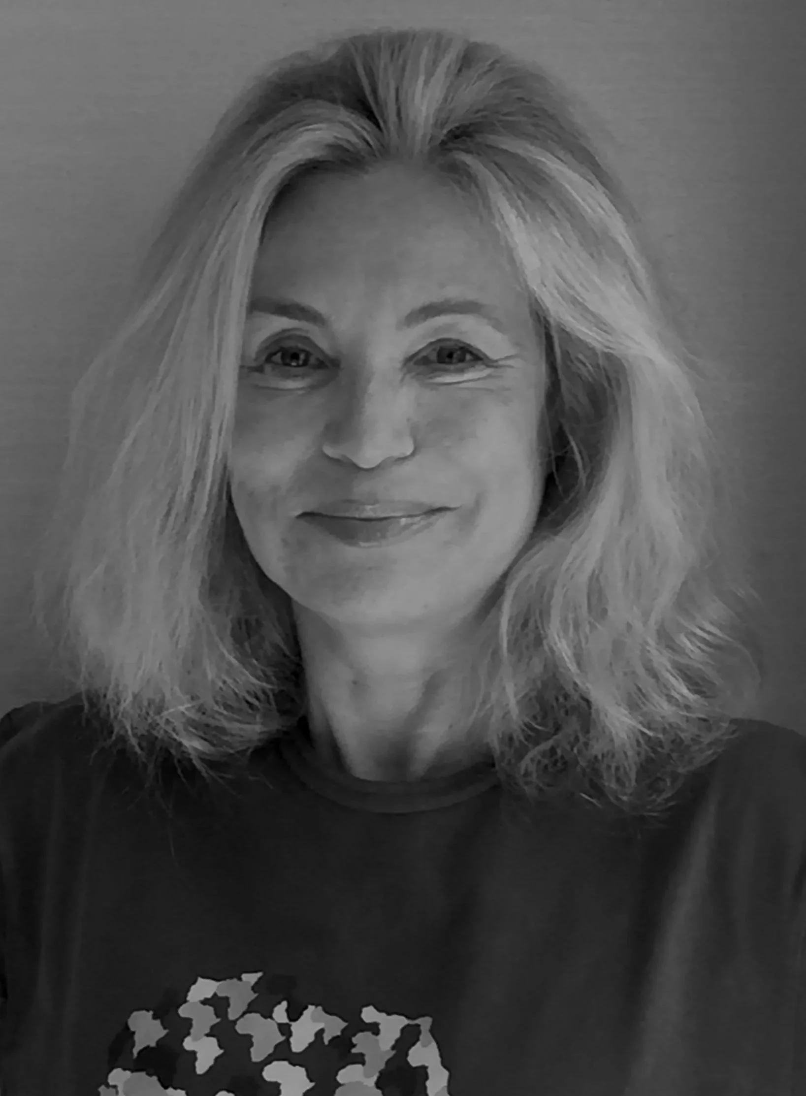 Black-and-white portrait of Bettina WitteVeen, Hypatia Co-Founder and Art Director for Design and Visual Language, smiling, with wavy shoulder-length hair.