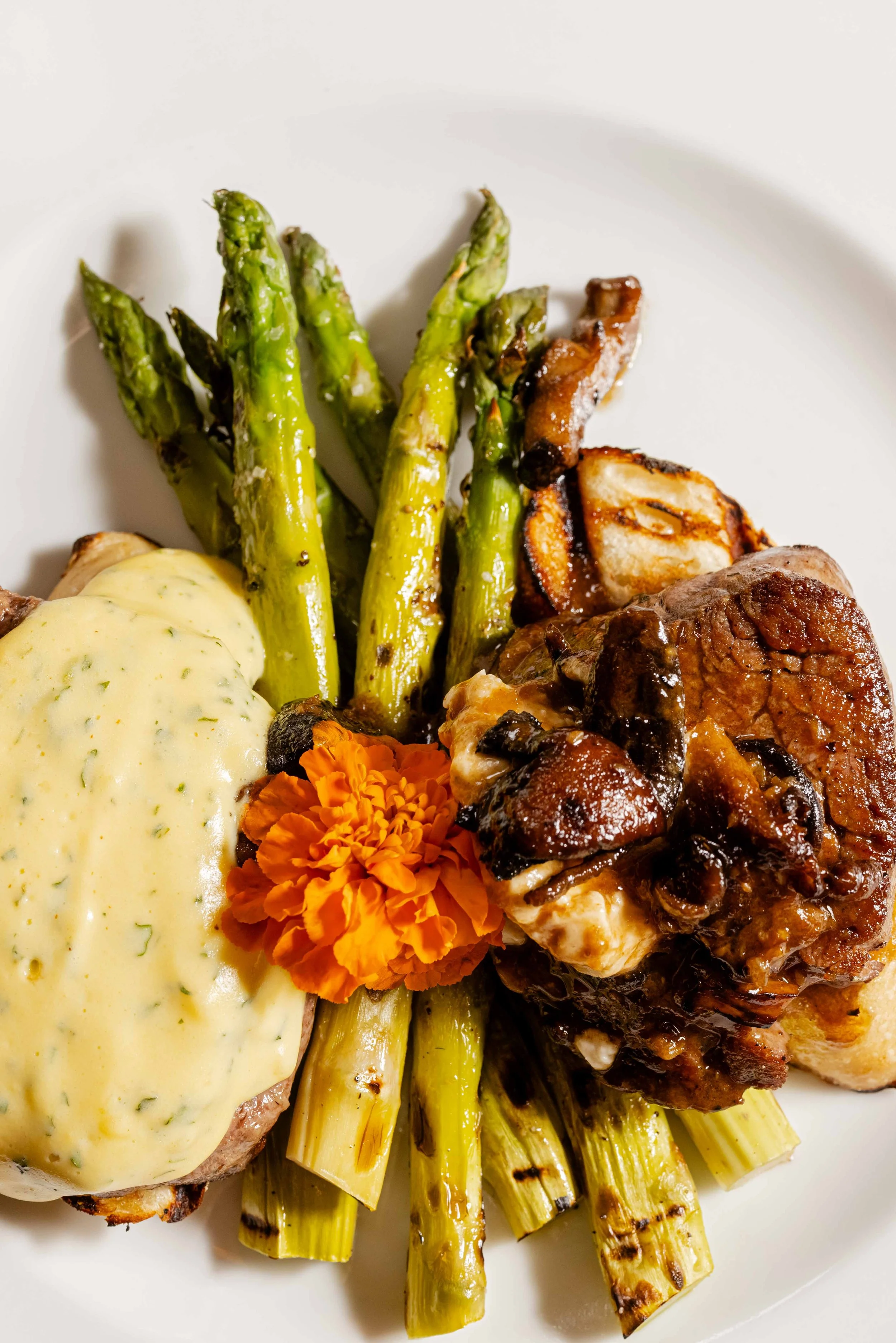 Grilled asparagus, roasted chicken with stuffing, and figurine of a chicken with gravy, garnished with a marigold flower
