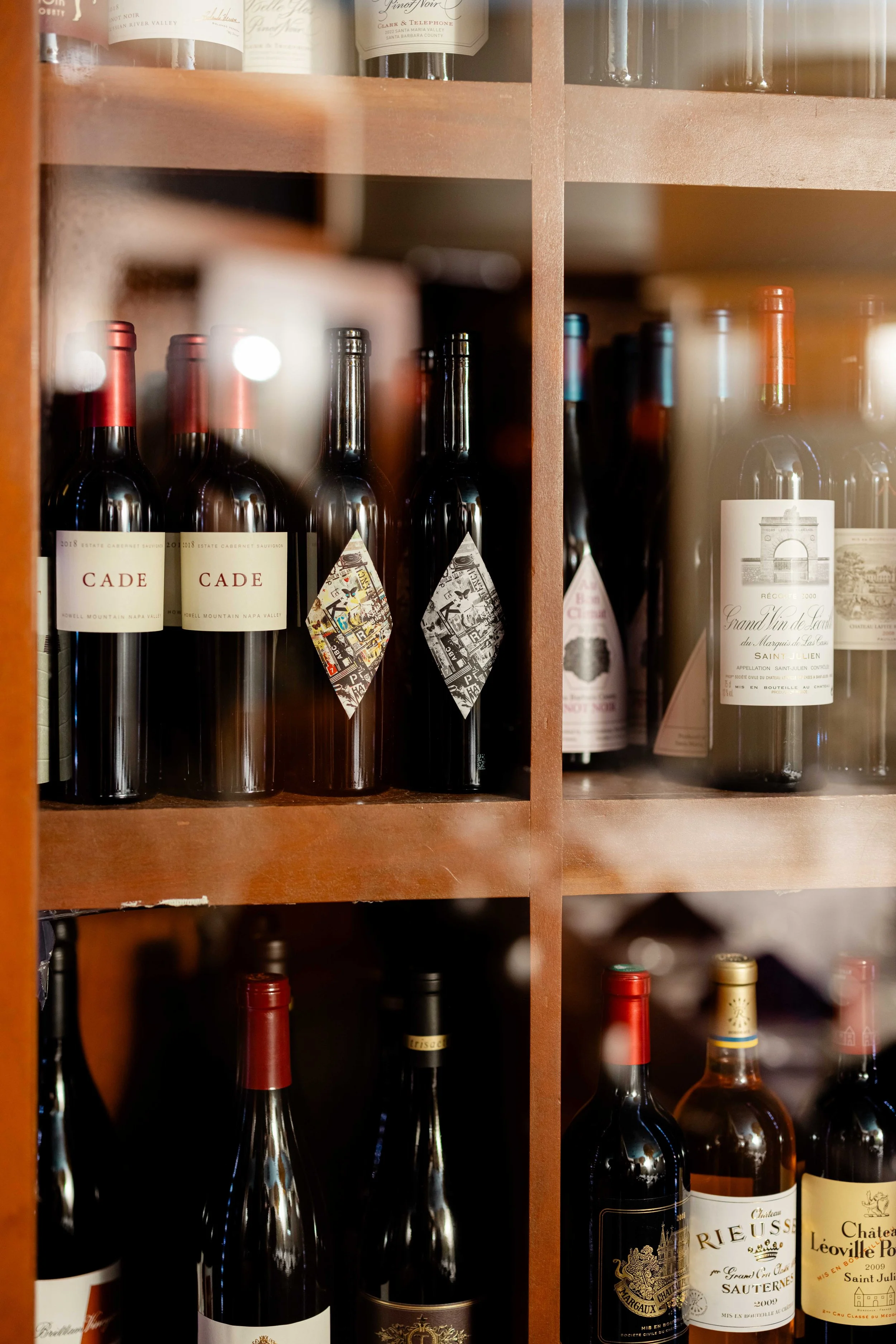 Shelf filled with various bottles of red wine.