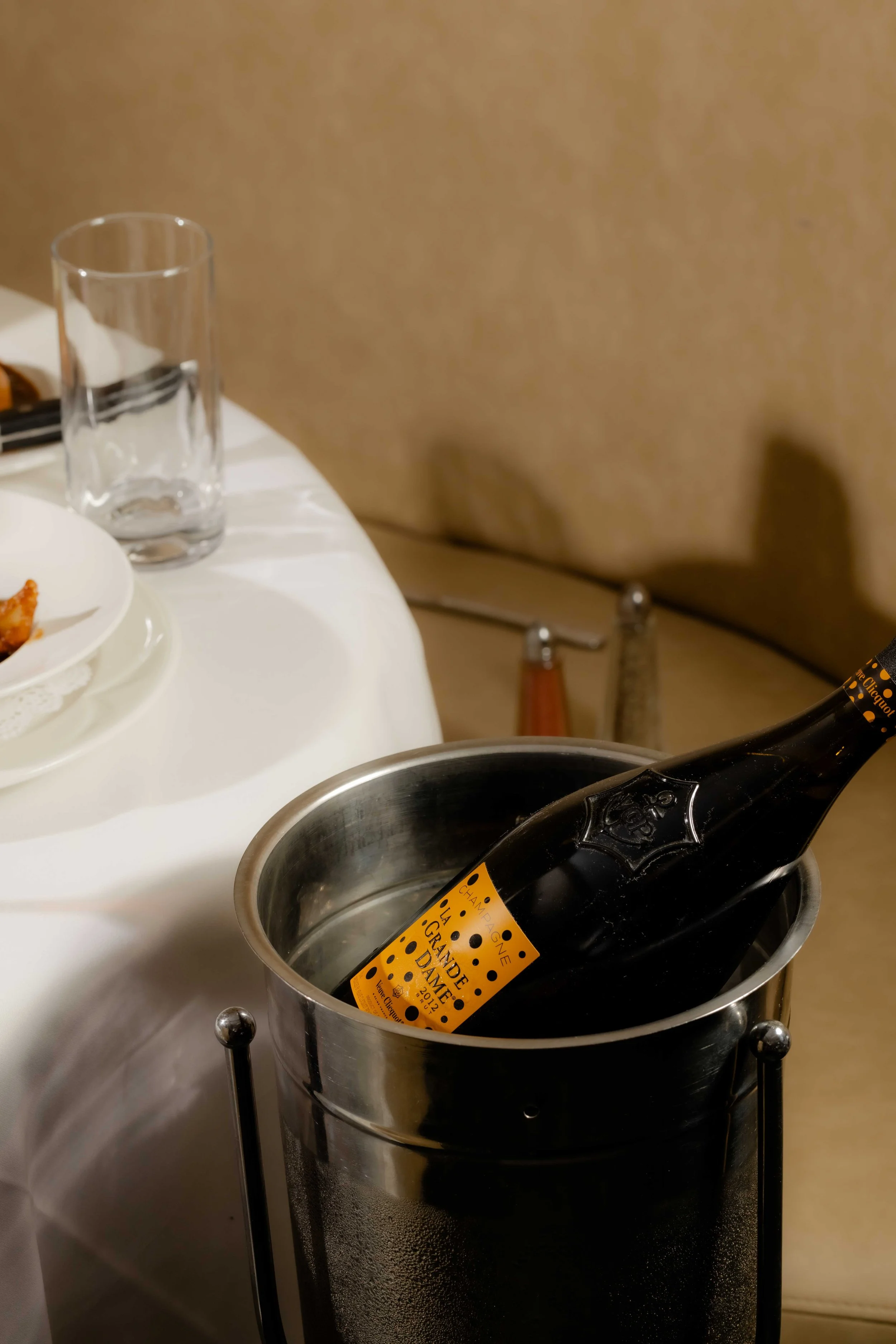 A bottle of champagne chilling in an ice bucket on a table at a restaurant.