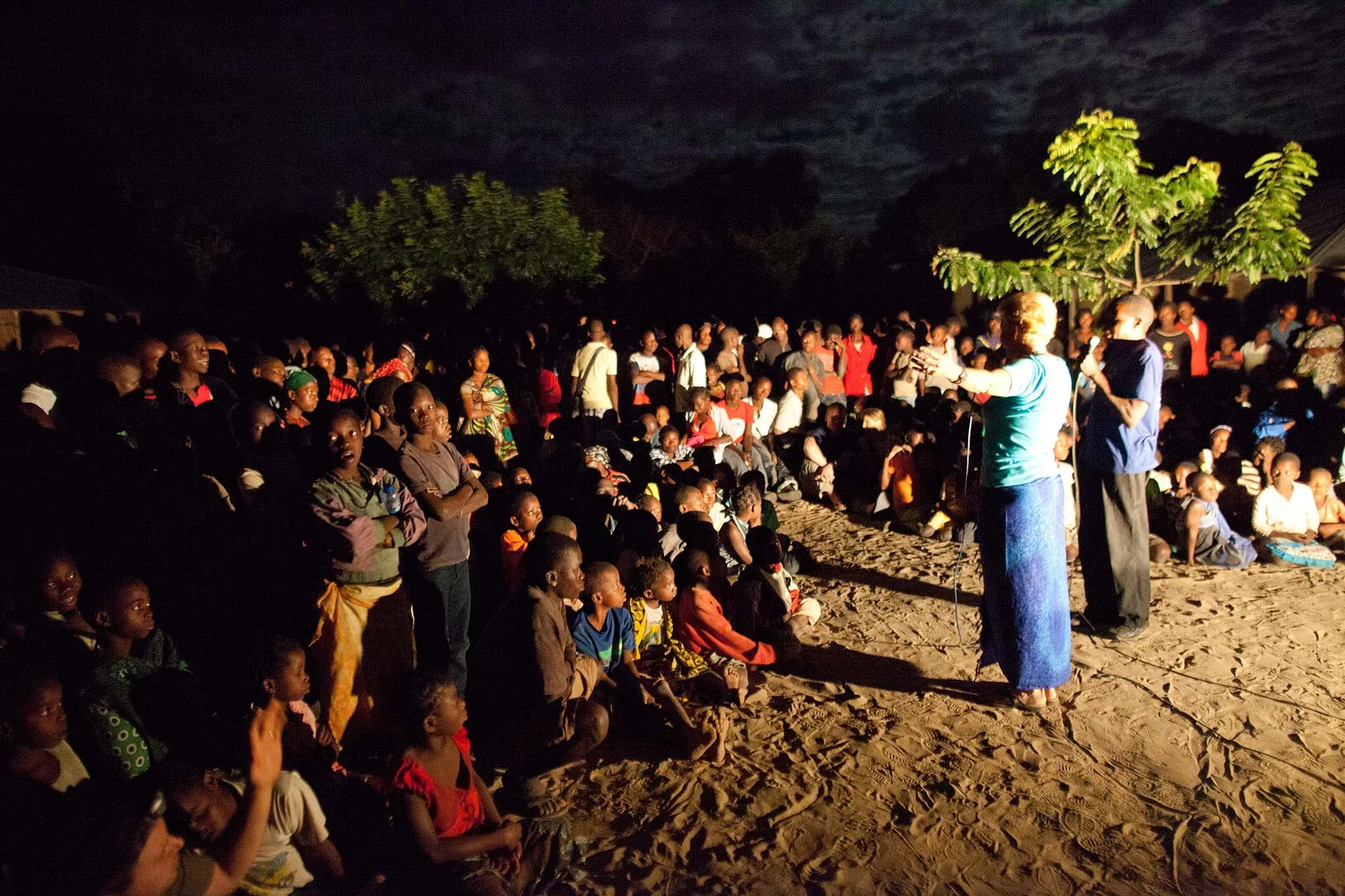 Preaching in the dim light and dirt at another village outreach