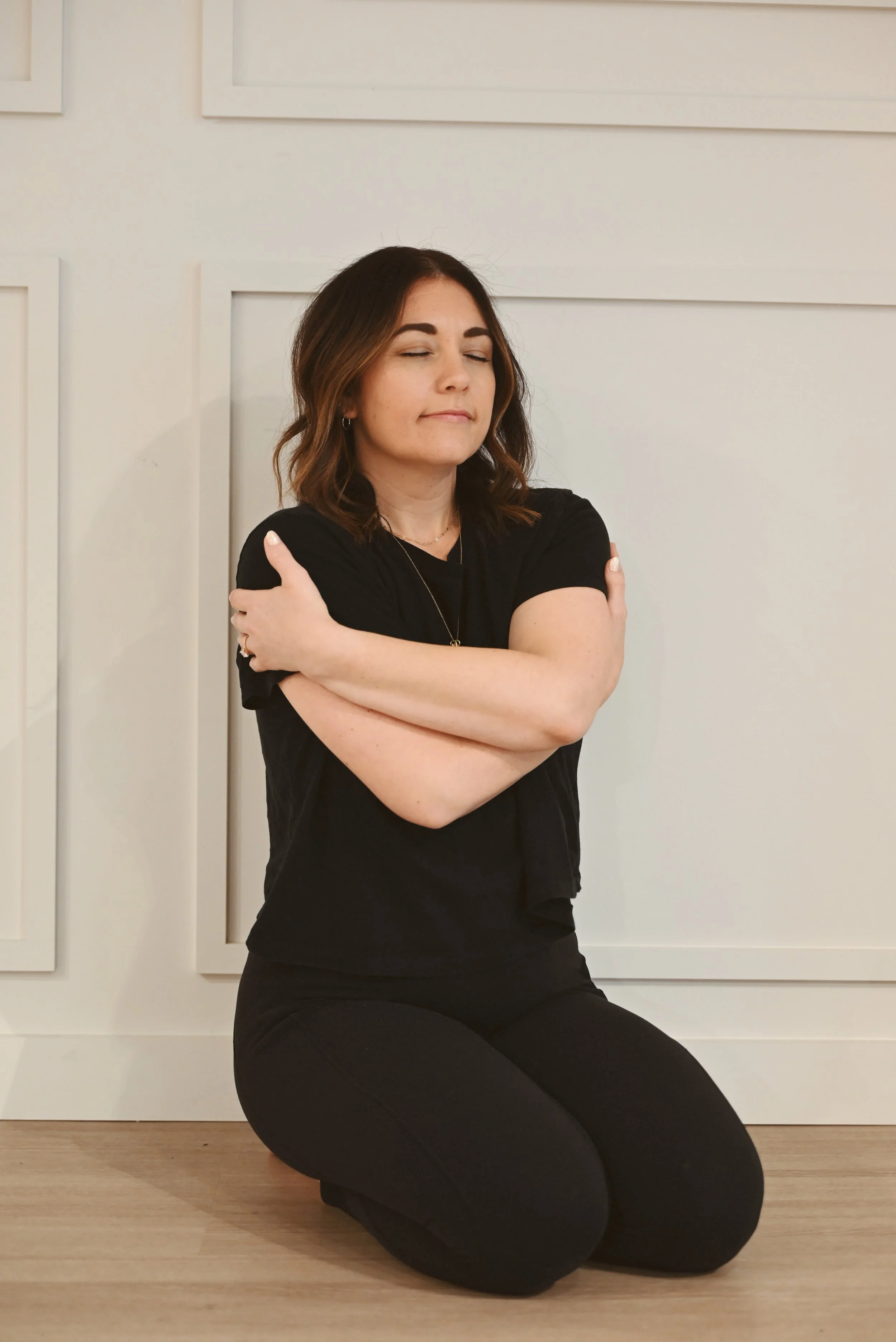 Mallory Tedrick gently hugging herself, symbolizing self-compassion and spiritual integration therapy, a holistic approach to trauma healing, body awareness, and emotional restoration