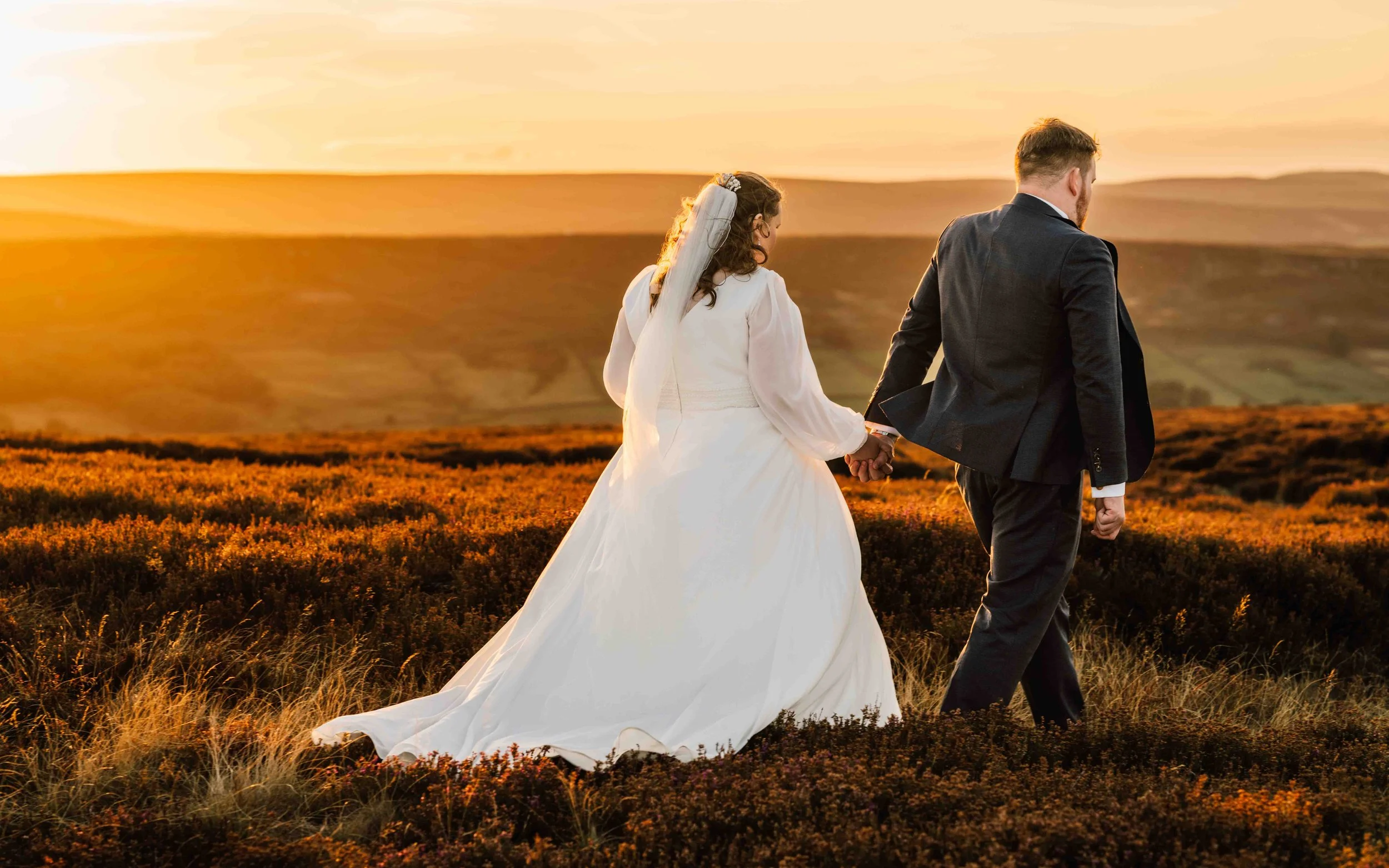 Couple walking across golden moorland at sunset