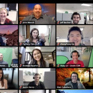 Screenshot of a virtual video conference with multiple participants, each in their own video window. Participants are smiling or waving, with various backgrounds including outdoor scenes and indoor offices.