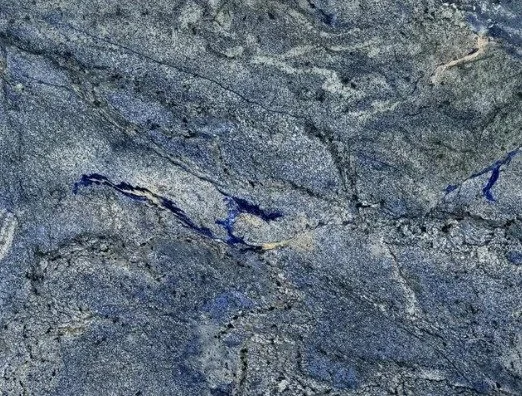 Close-up of blue-gray granite with flowing dark veins, vivid blue accents, and subtle cream mineral streaks.