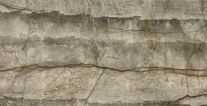 Close-up of a cracked and weathered stone or concrete surface with visible lines and texture.