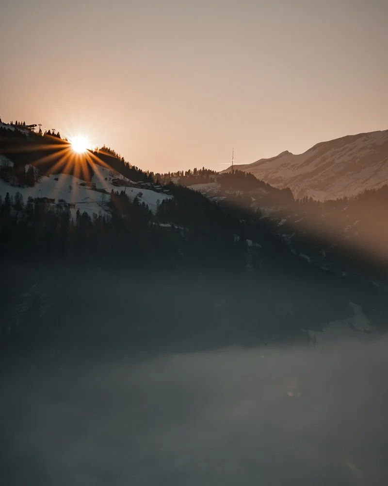 Sonnenaufgang über verschneiten Berggipfeln und einem Nebelmeer in den Bergen.