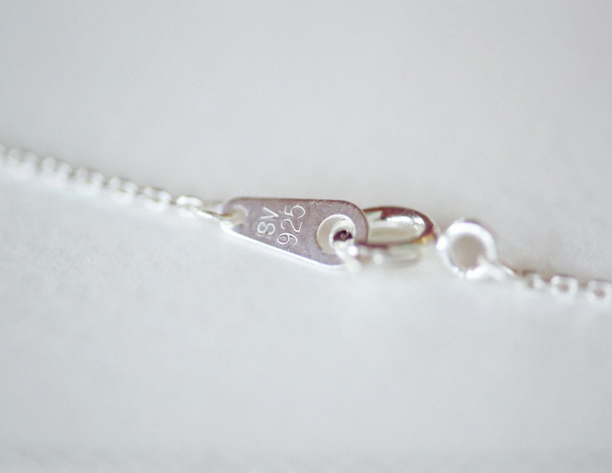 Close-up of a silver jewelry clasp marked 'SV 925' on a chain.