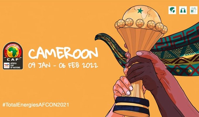 Affiche orange représentant deux mains, une claire et une foncée, tenant une coupe de la CAN 2021 de football, avec le texte ''Cameroon 09 Jan - 06 Fév 2022'' et le logo de la CAF.