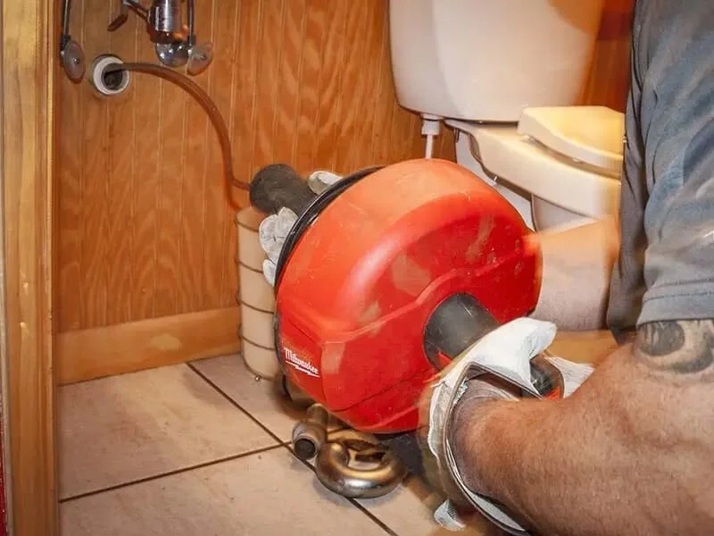 septic drain cleaning using powered auger machine indoors