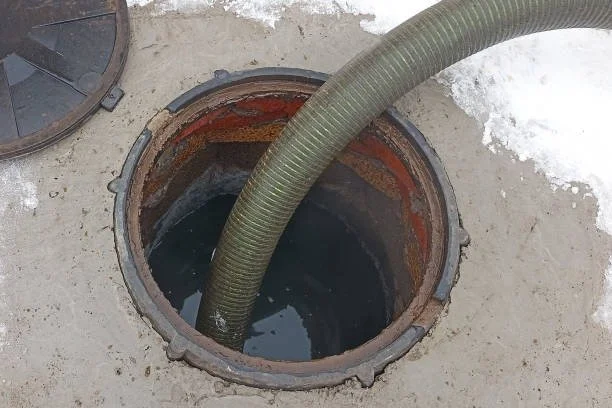 septic tank pumping with vacuum hose inside access opening