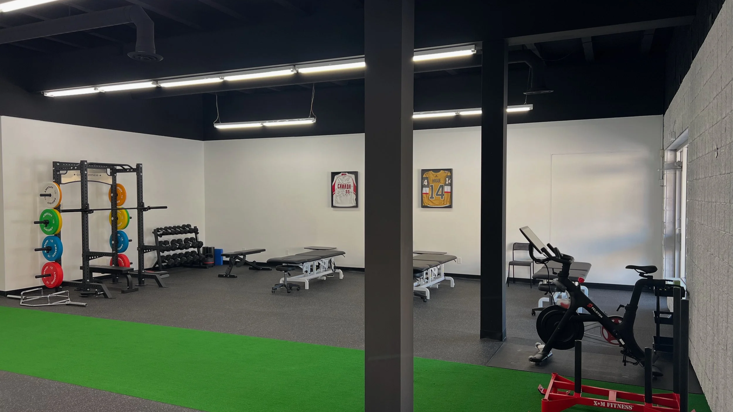 Split view of a gym interior with weightlifting and cardio equipment, including colorful weight plates, dumbbells, benches, exercise bikes, and framed sports jerseys on the walls.
