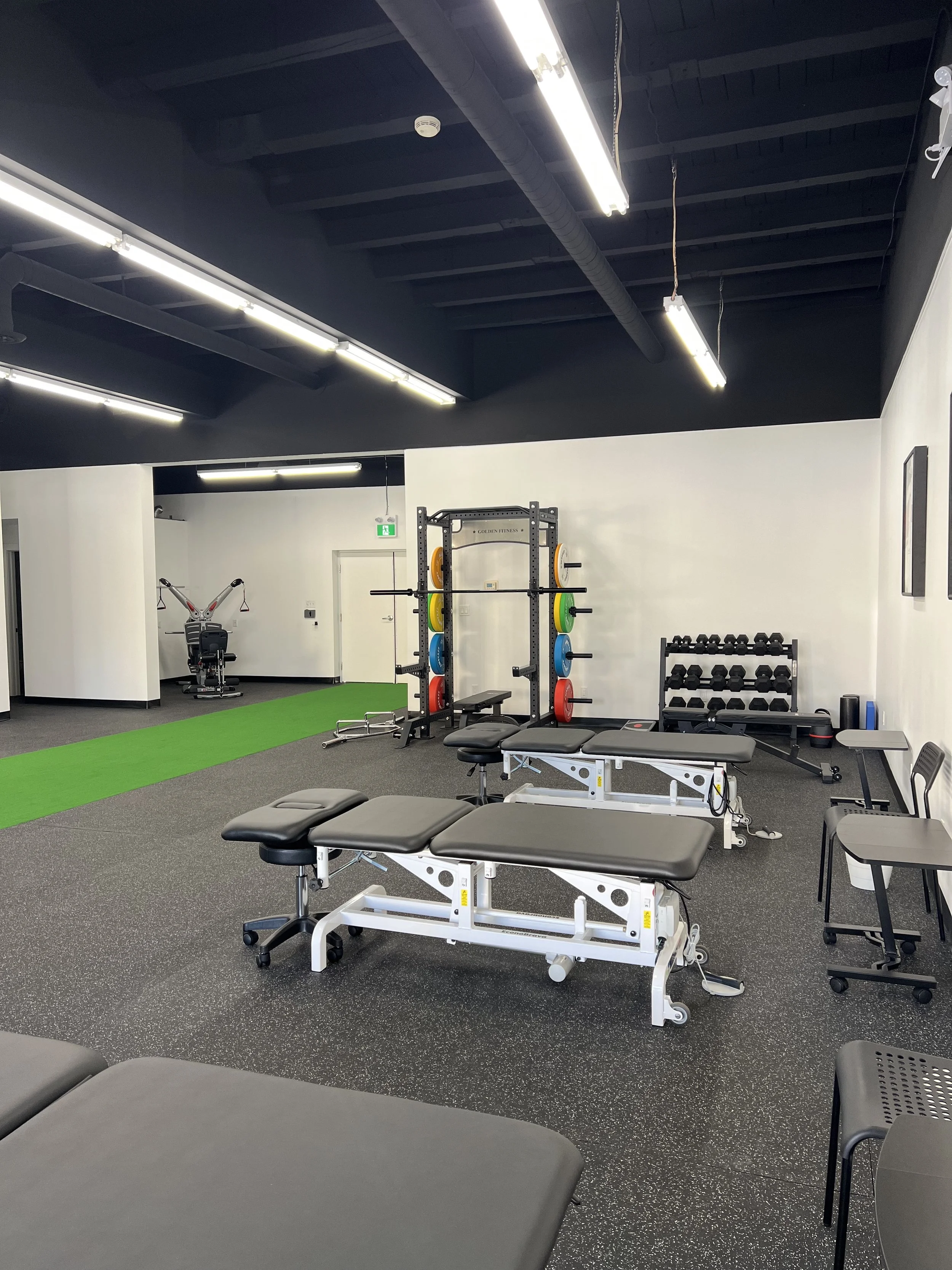 Gym with workout benches, dumbbell rack, weight plates, and exercise equipment.