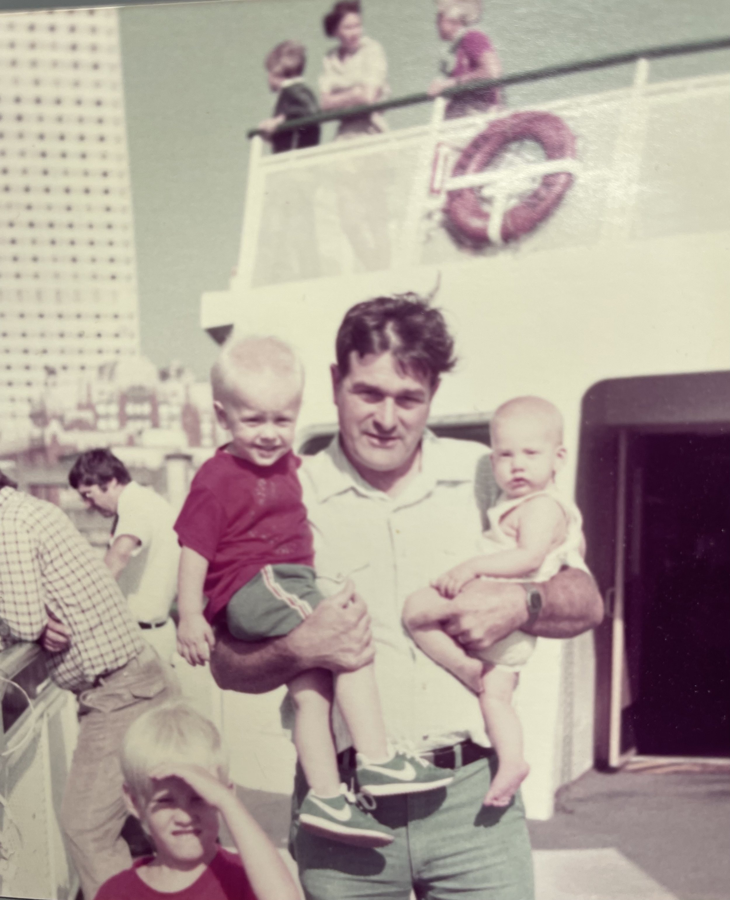 Man holding two babies while on a boat