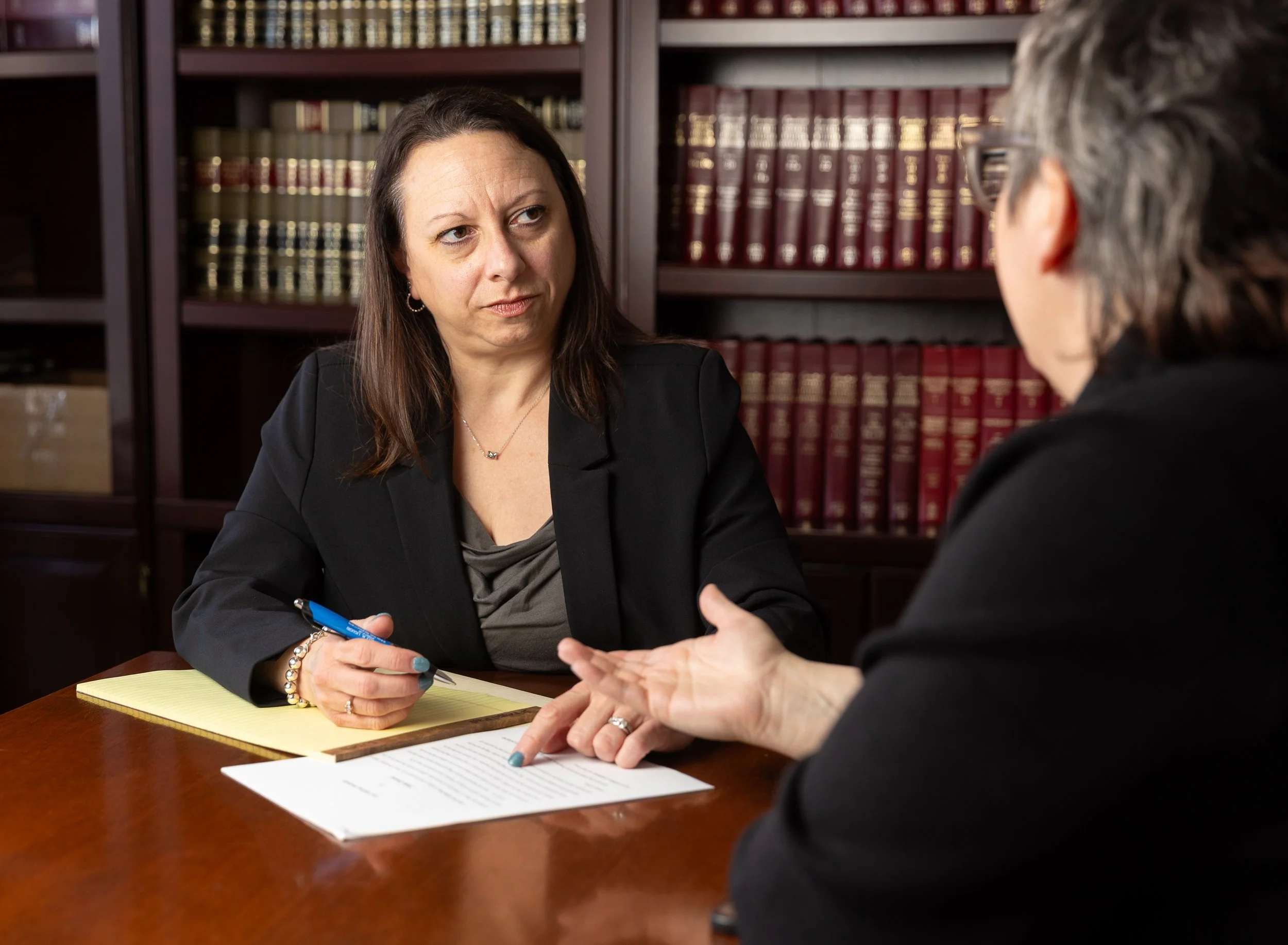 Michelle Liguori having a discussion with a client in her office, with shelves of books in the background.