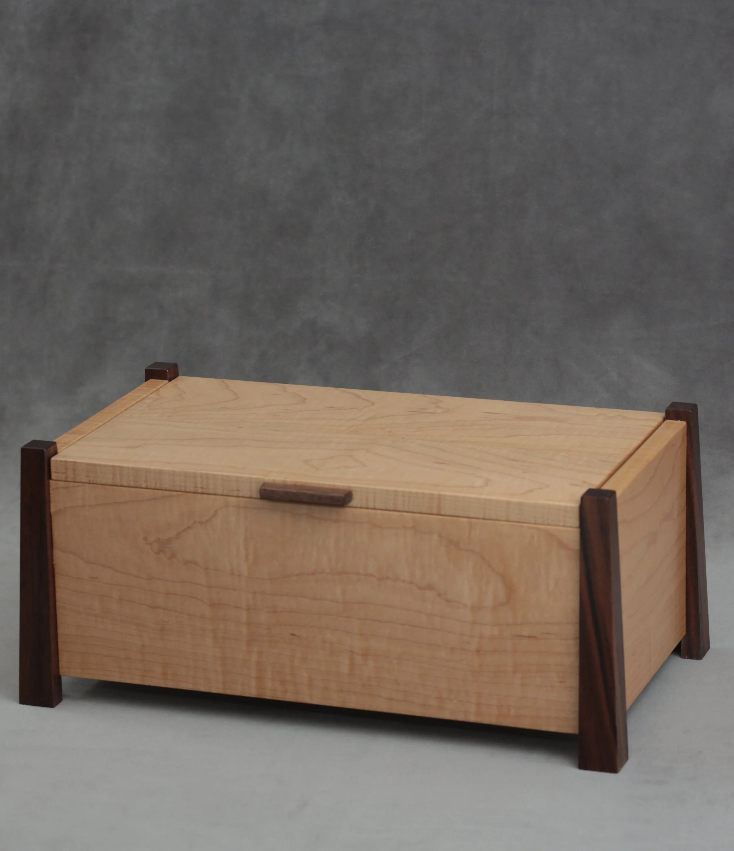 A wooden storage box with dark wooden supports and a lid, placed against a gray background.