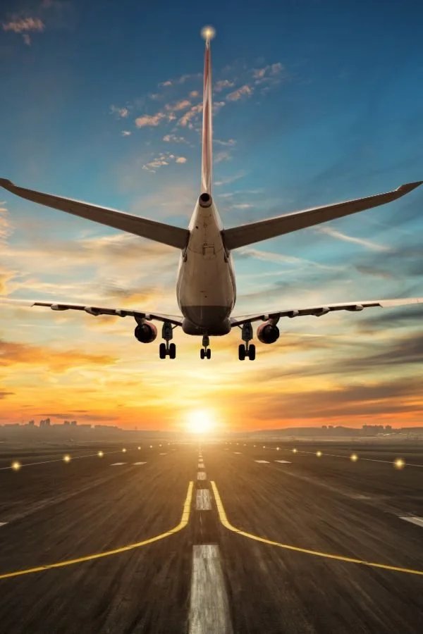 Airplane taking off into vibrant sunset sky