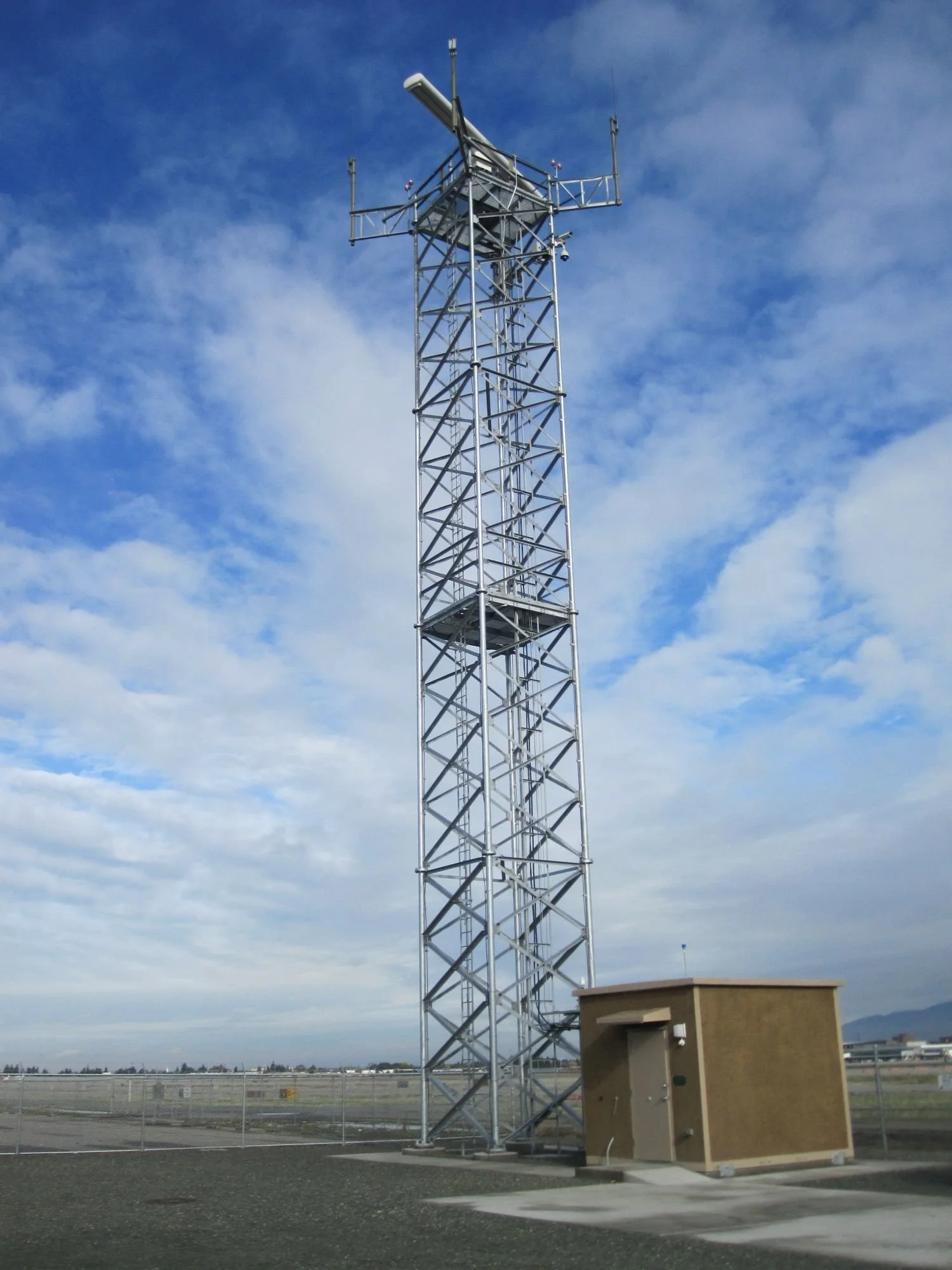 Surface movement radar tower installation with adjacent communication shelter at airport