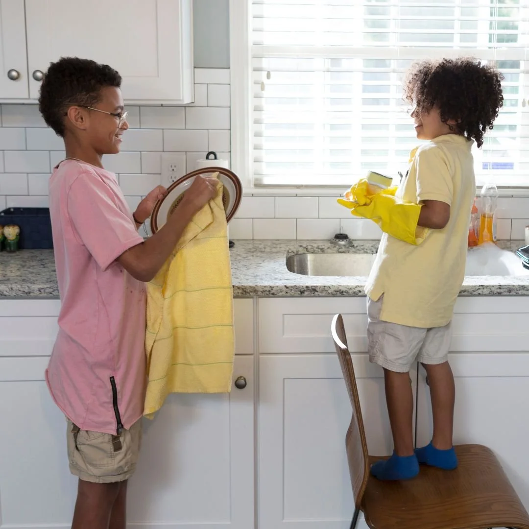 Two young boys washing dishes together