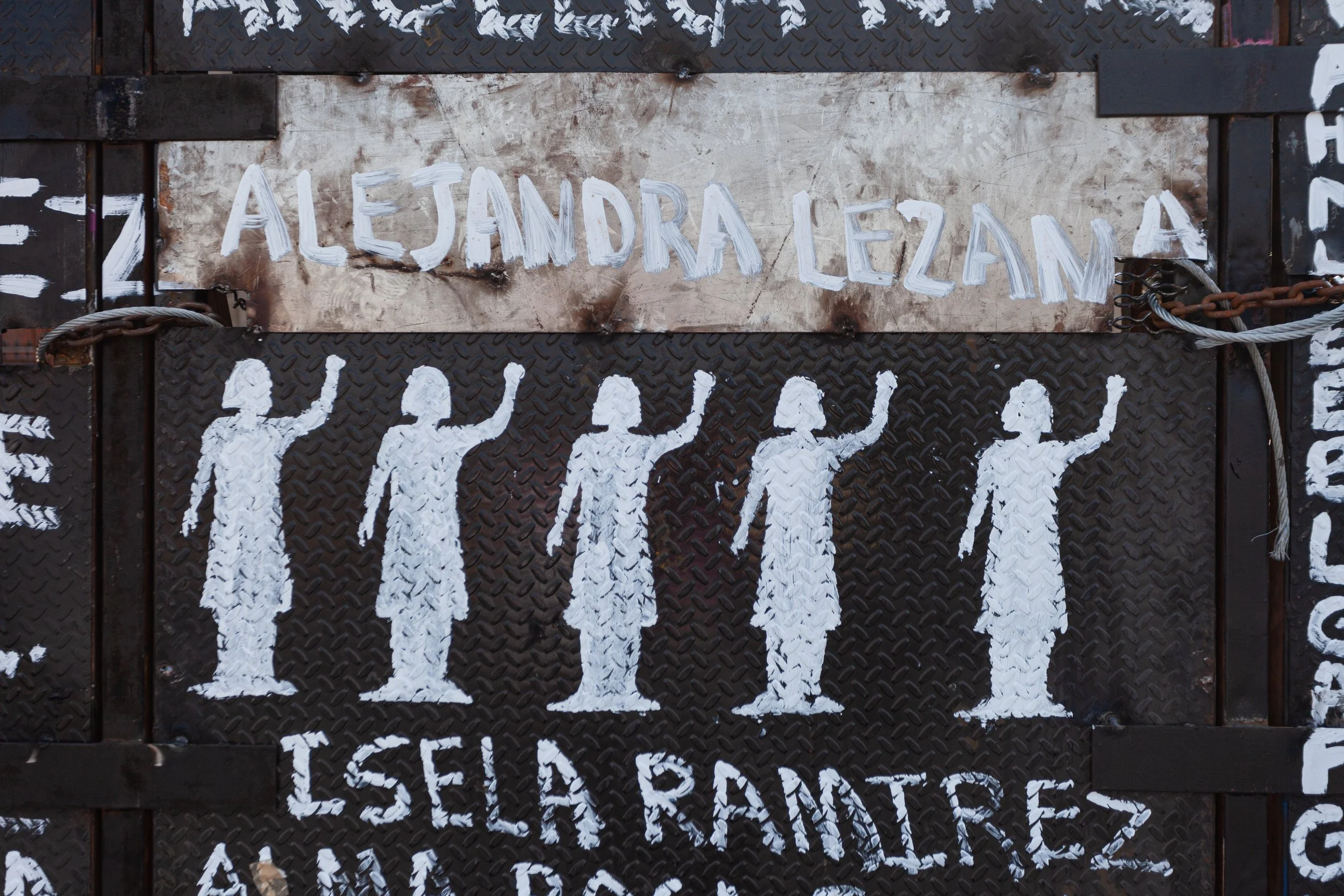 Five stencils in white of girls with their arms raised painted on black metal