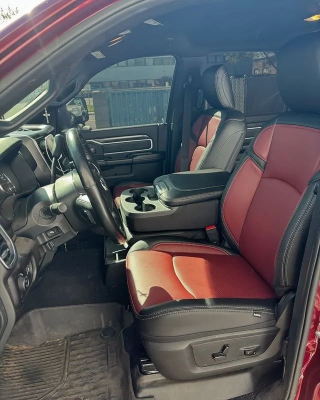 Interior of a pickup truck with black and red leather seats, a black dashboard, and cup holders in the center console.