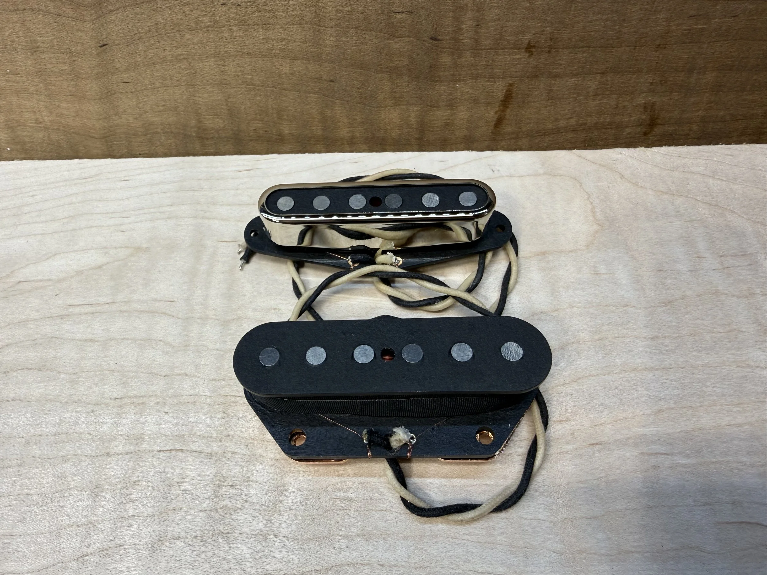 single coil Telecaster pickup set with black and chrome finish, mounted on black and chrome pickup cover, placed on a light wood surface. radnor guitars stone age telecaster set.