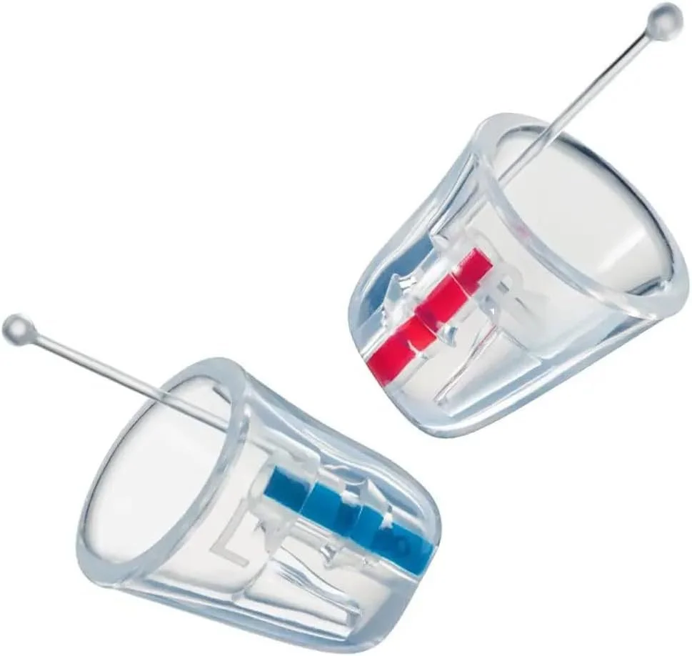Two transparent plastic containers with blue and red switches and long metal pins, tipped with rounded ends, resting against a plain white background.