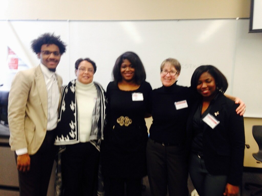 Woman at podium presenting in a large conference room with a screen behind her displaying 'Empowering Future Leaders