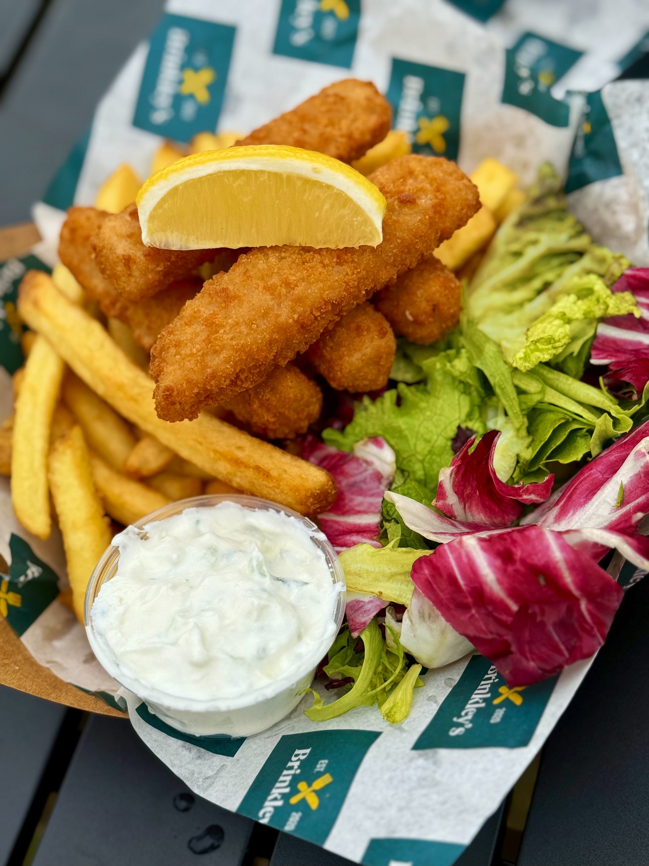 Fried fish fillets with lemon wedge, french fries, side salad, and tartar sauce