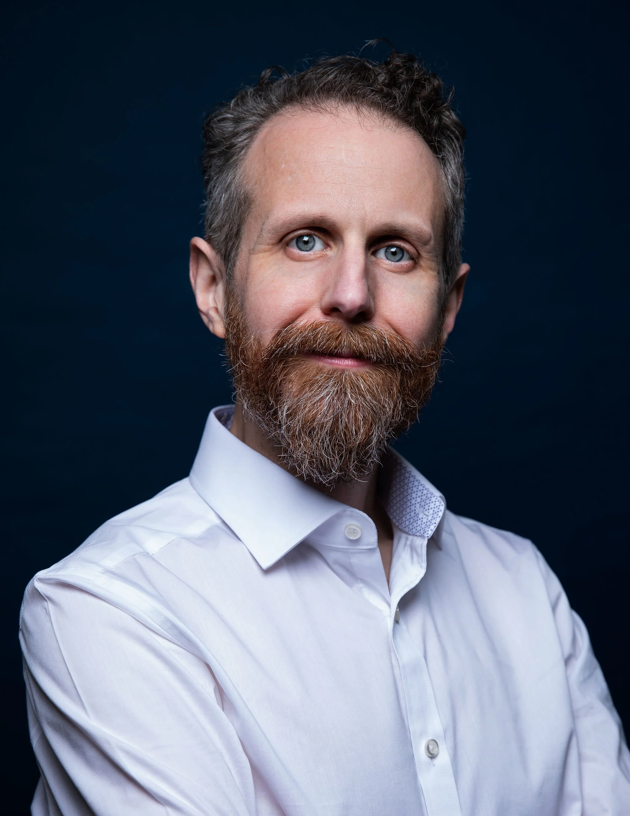 Actor Jonathan Laury in a white shirt and dark blue background