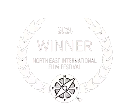 Award emblem with laurel wreath, text indicating 2024 Winner at North East International Film Festival, with a fuel gauge and compass in the center.