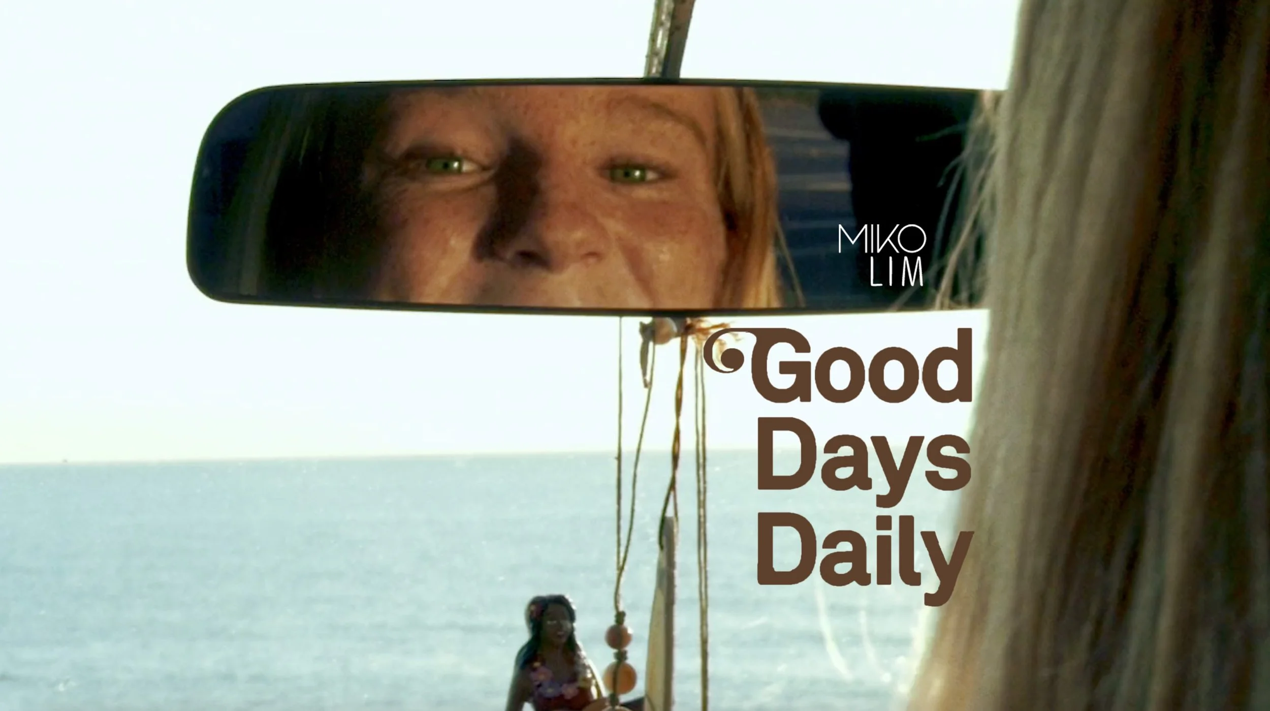 A person relaxing with their legs out of a car window at sunset, wearing white socks with a hot dog design and the words 'Truly The Best' on them, near the beach with the message 'Good Days Daily' overlaid.