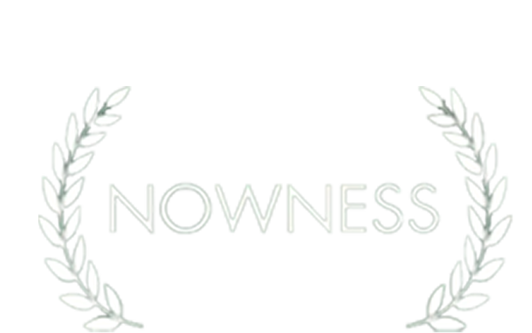 A digital logo with the word 'NOWNESS' in white letters, surrounded by a laurel wreath on a black background.